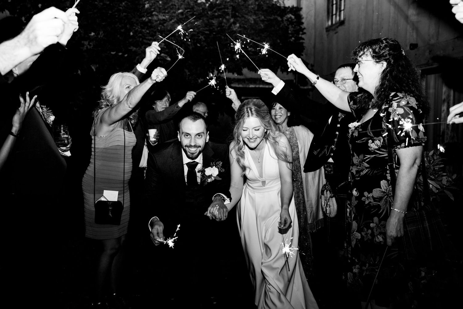 Wedding guests at the Farm at South Cove celebrating by showering the couple with sparklers during a wedding reception outside the barn.