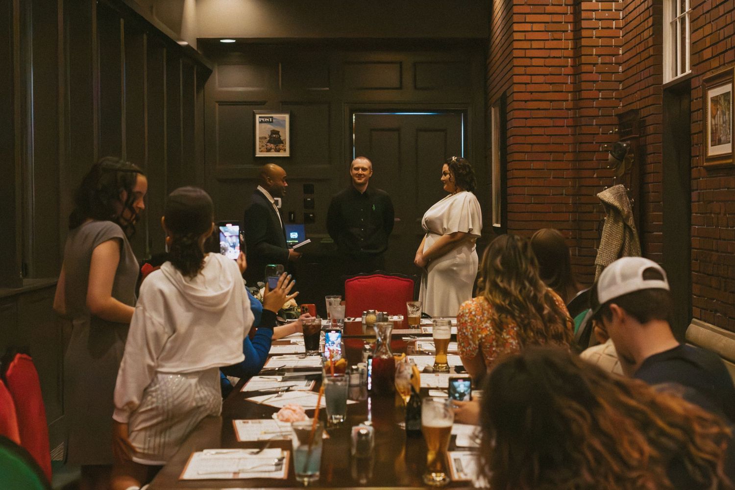 Restaurant dining room with brick walls and warm lighting showing a group gathered for a meal.