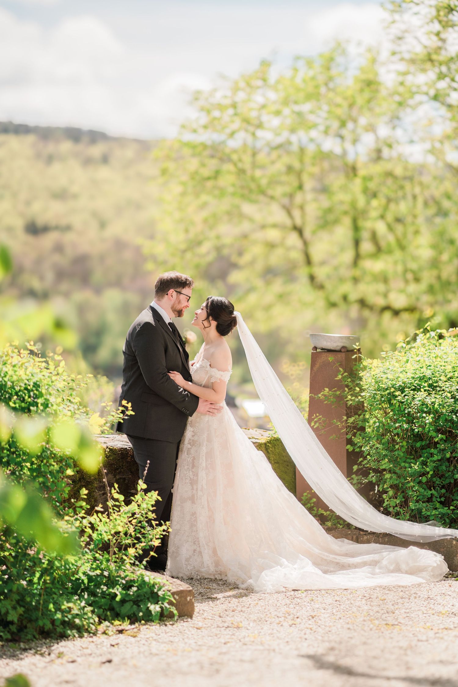 Couple sharing romantic moment in elegant wedding attire against scenic mountain backdrop.