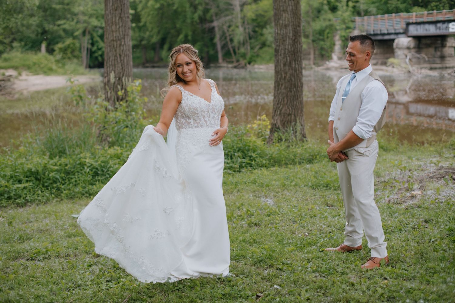 A couple shares their first look moment at an outdoor wedding venue with natural greenery and stone walls.