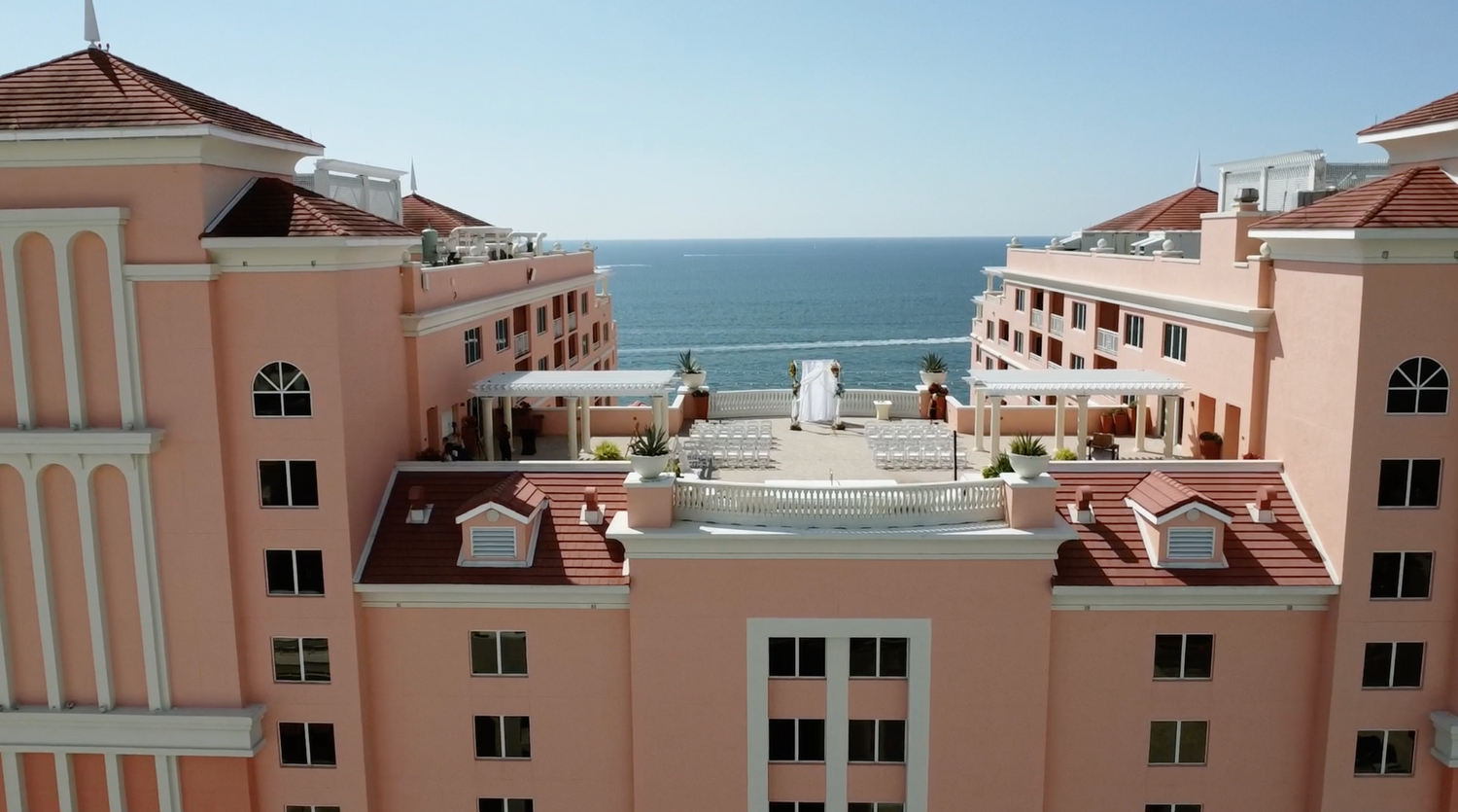 Aerial view of a pink Mediterranean-style resort building complex overlooking the ocean.