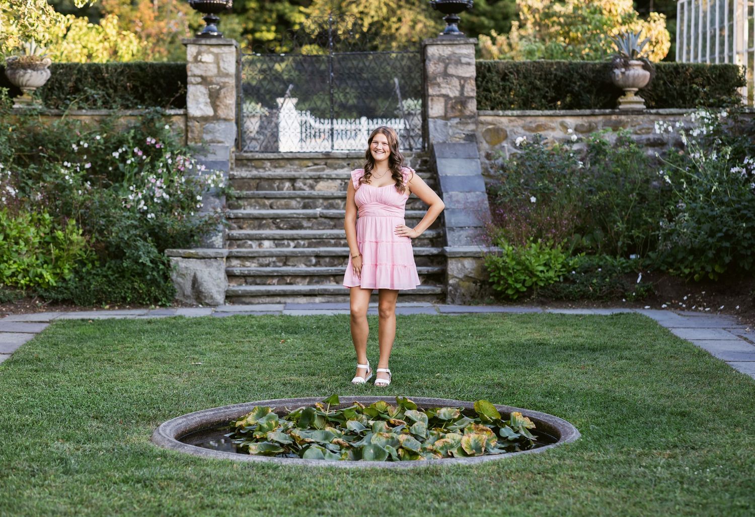 Senior photoshoot at Stevens Coolidge House North Andover of girl with long brown hair in a pink dress in a garden setting with stone steps.