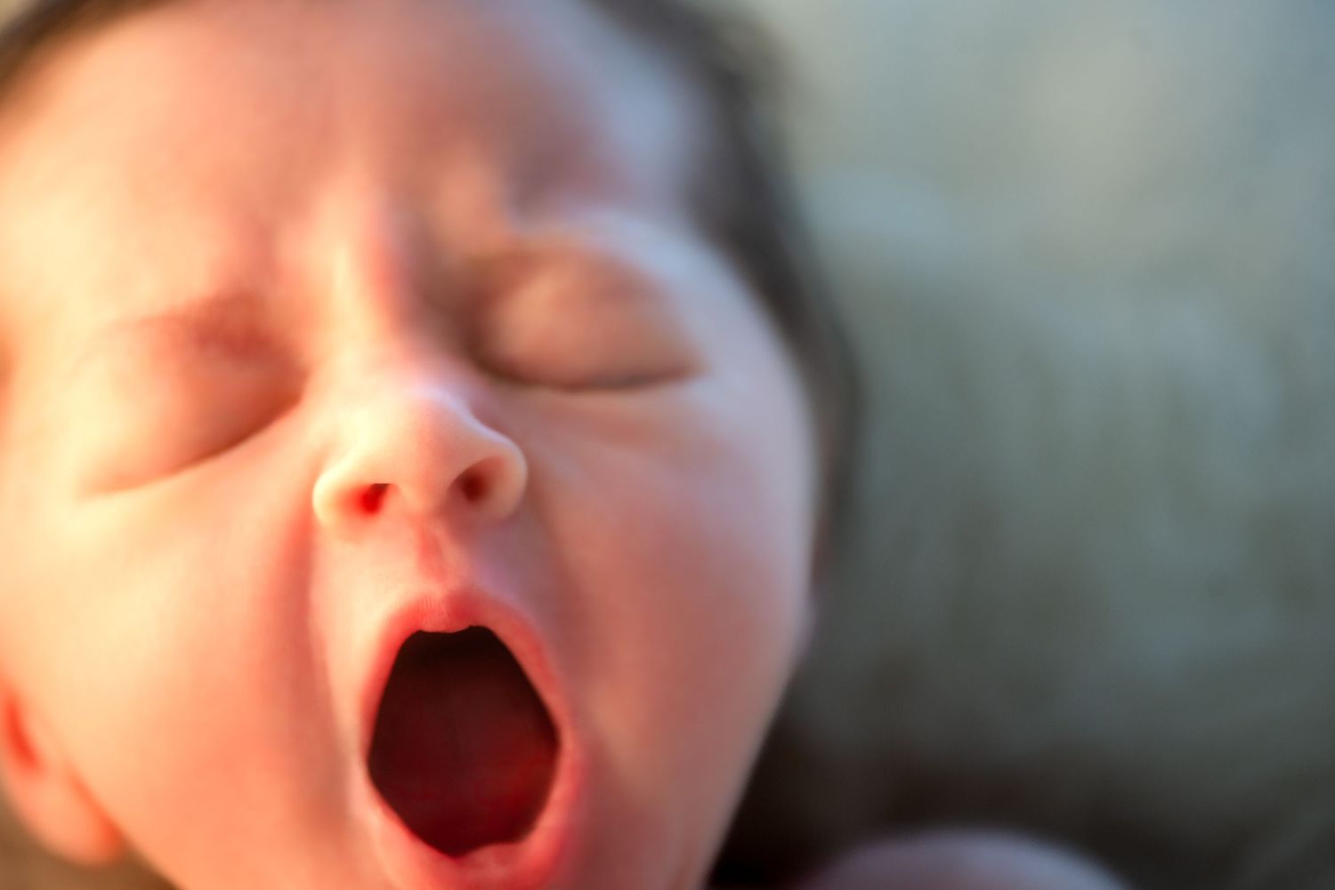 Four close-up photos showing a baby yawning and making different facial expressions.