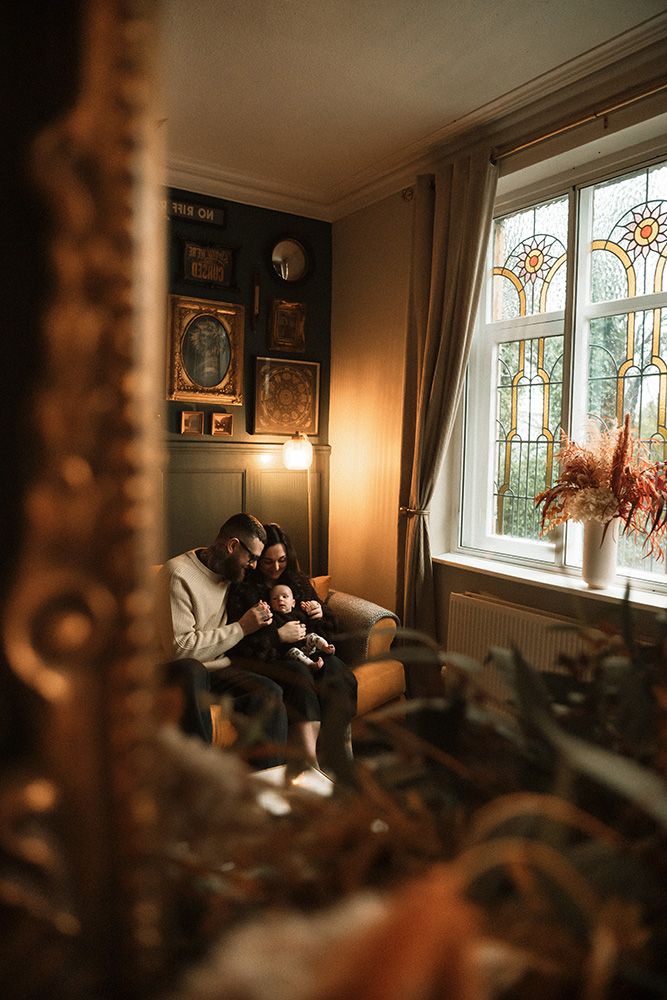 Manchester newborn photographer. Cozy living room interior with stained glass windows and warm lighting creates an intimate atmosphere.