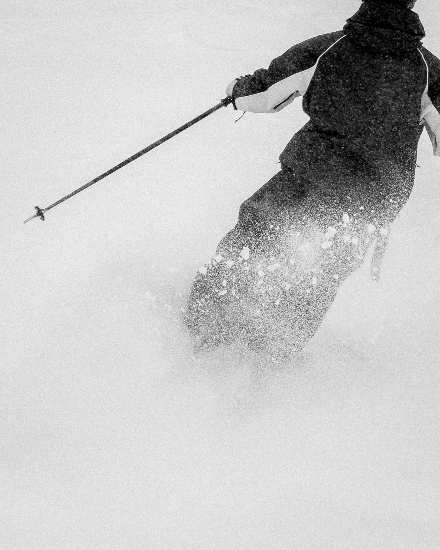 A skier carves through deep powder snow creating a dramatic spray against a white winter background.