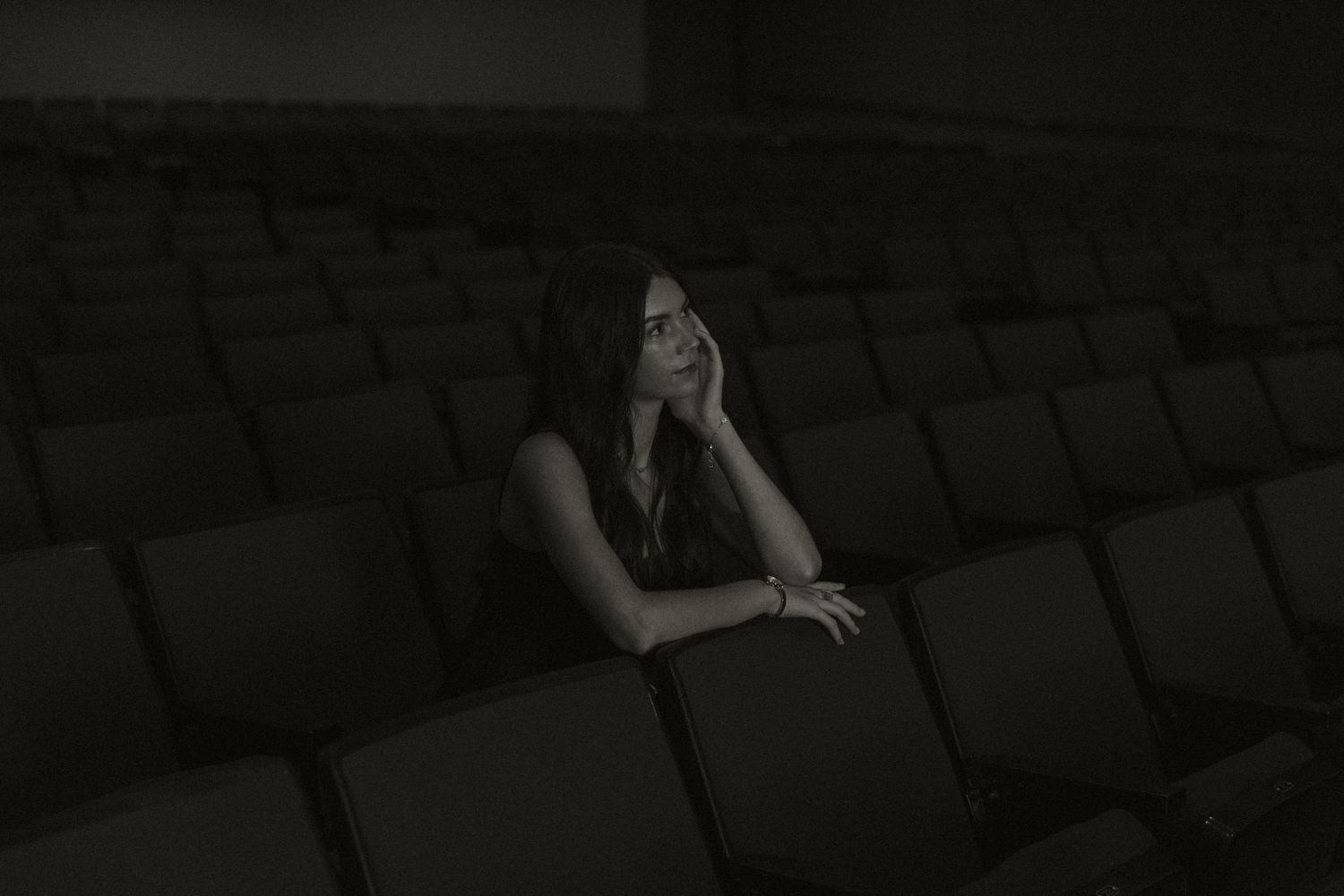 A dramatic black and white photo of someone reclining across theater seats.