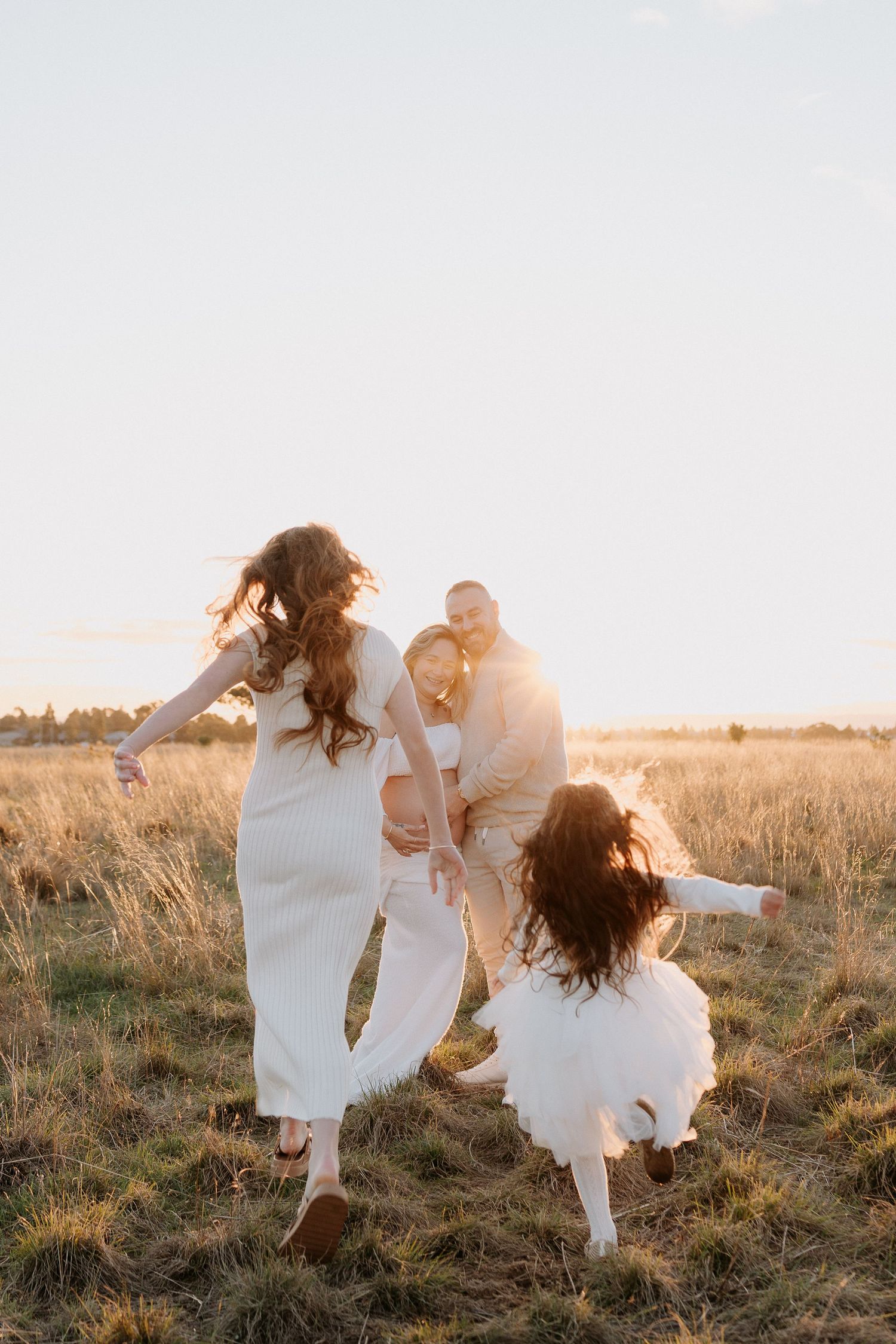 A group in white outfits walks together across a sunlit field.