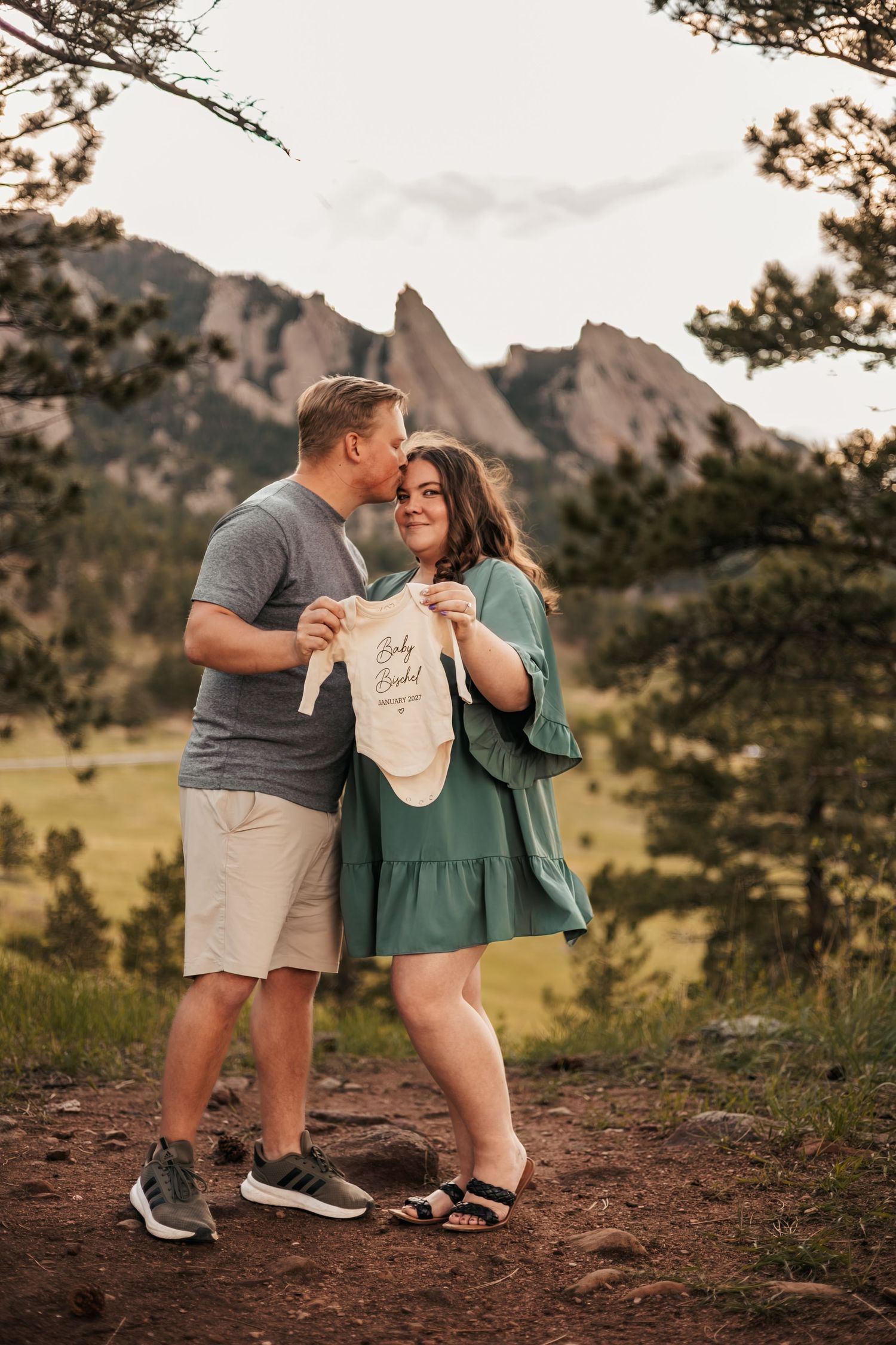 Couple holding baby onesie for pregnancy announcement | Baby Announcement Photographer in Boulder, Colorado