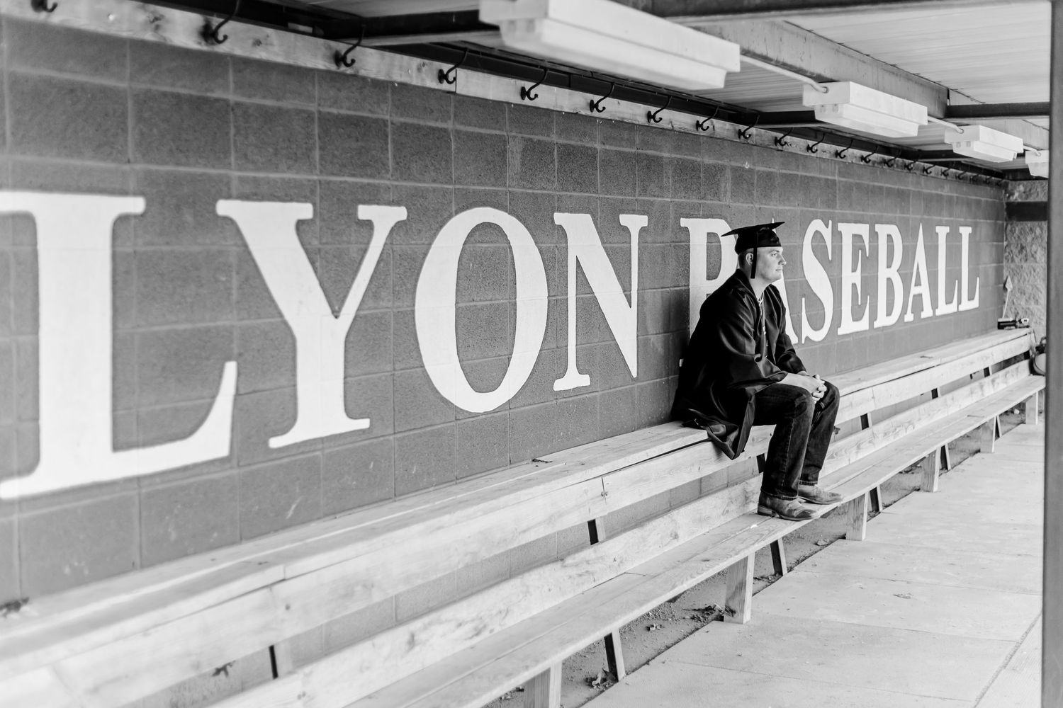 Vintage black and white photo of someone sitting alone in baseball stadium bleachers with Lyon signage.