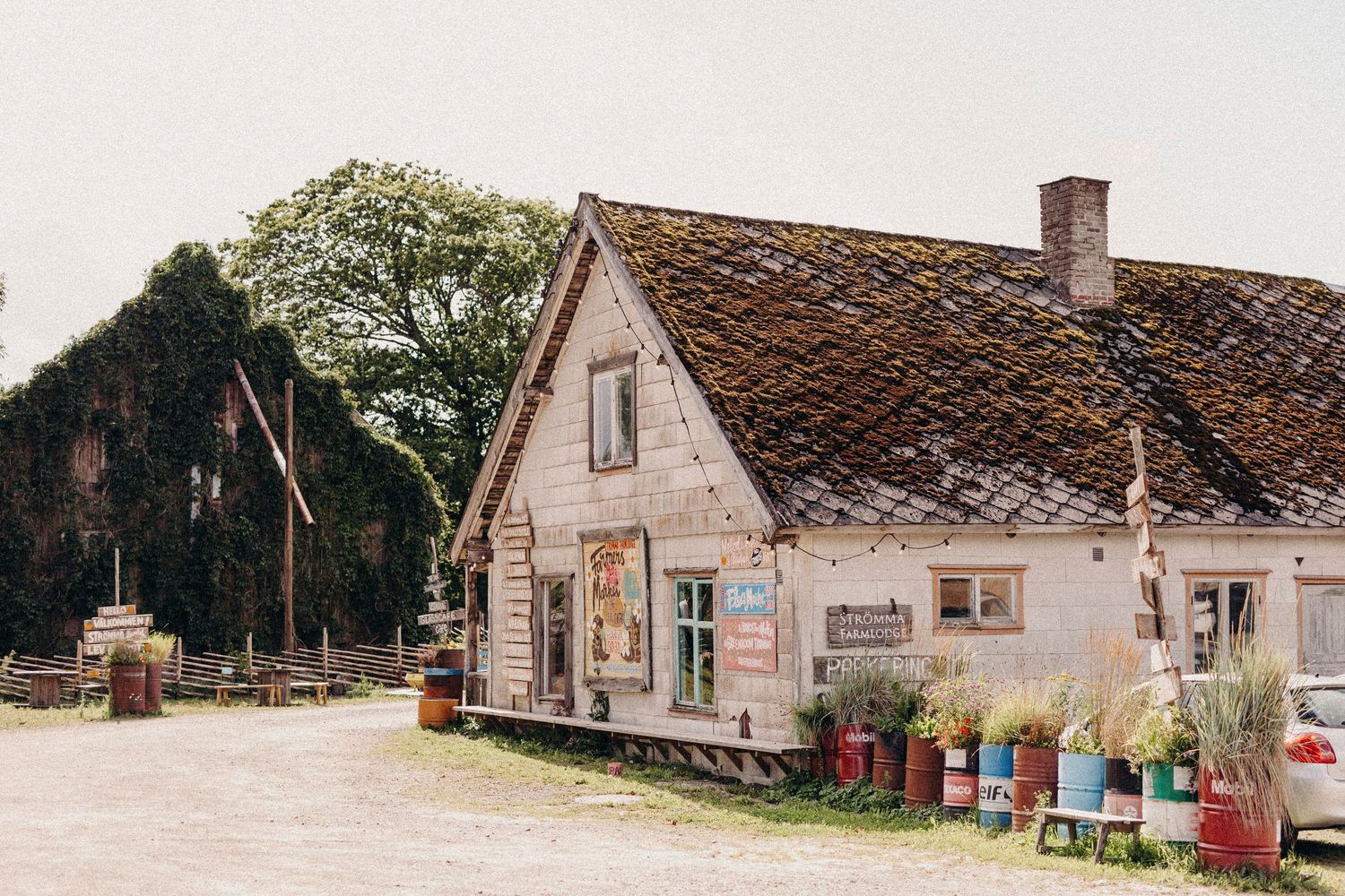 A rustic wooden barn or stable building with banner signage and twinkle lights hanging from the exterior walls.