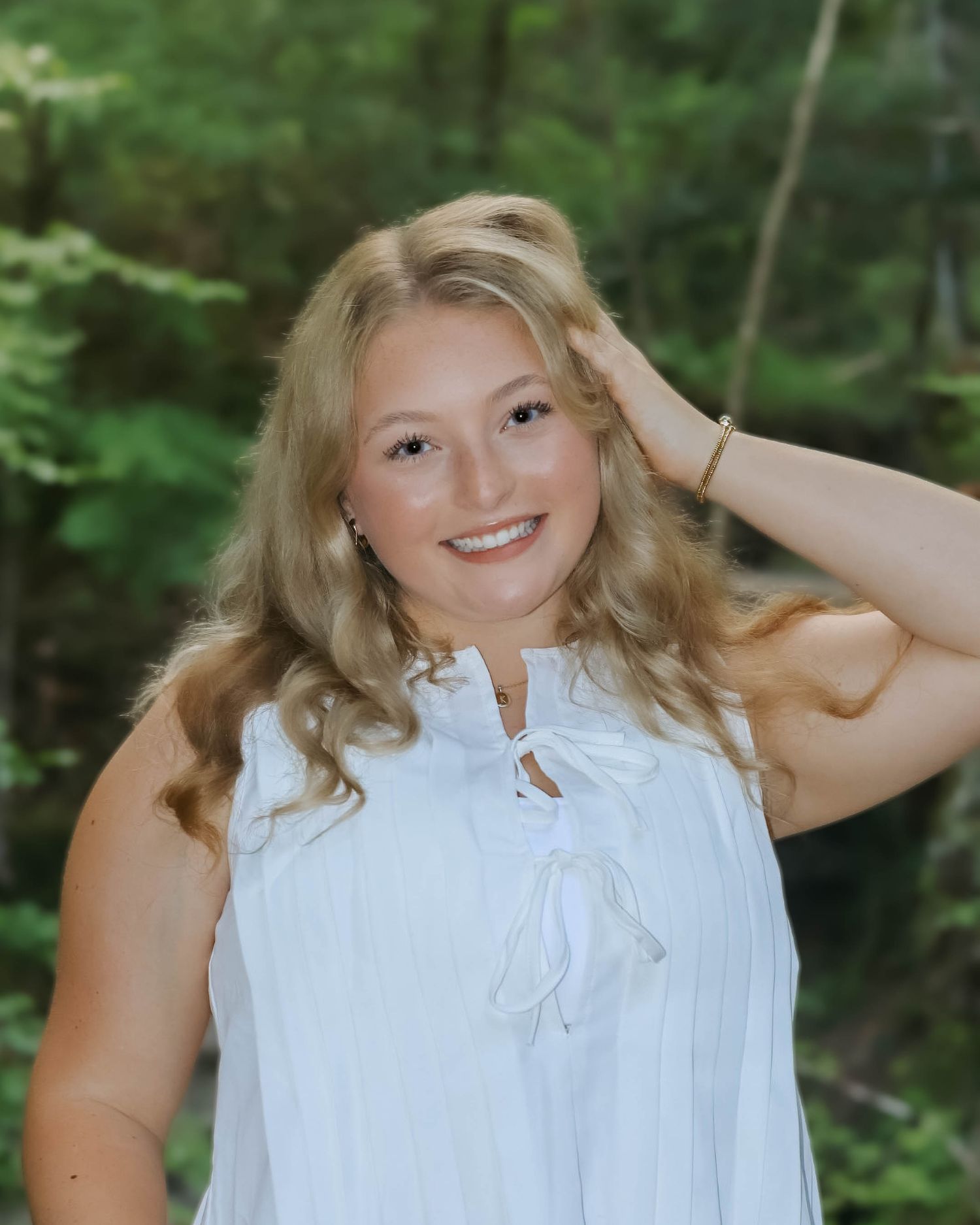 Summer portrait in white sleeveless top against forest background.