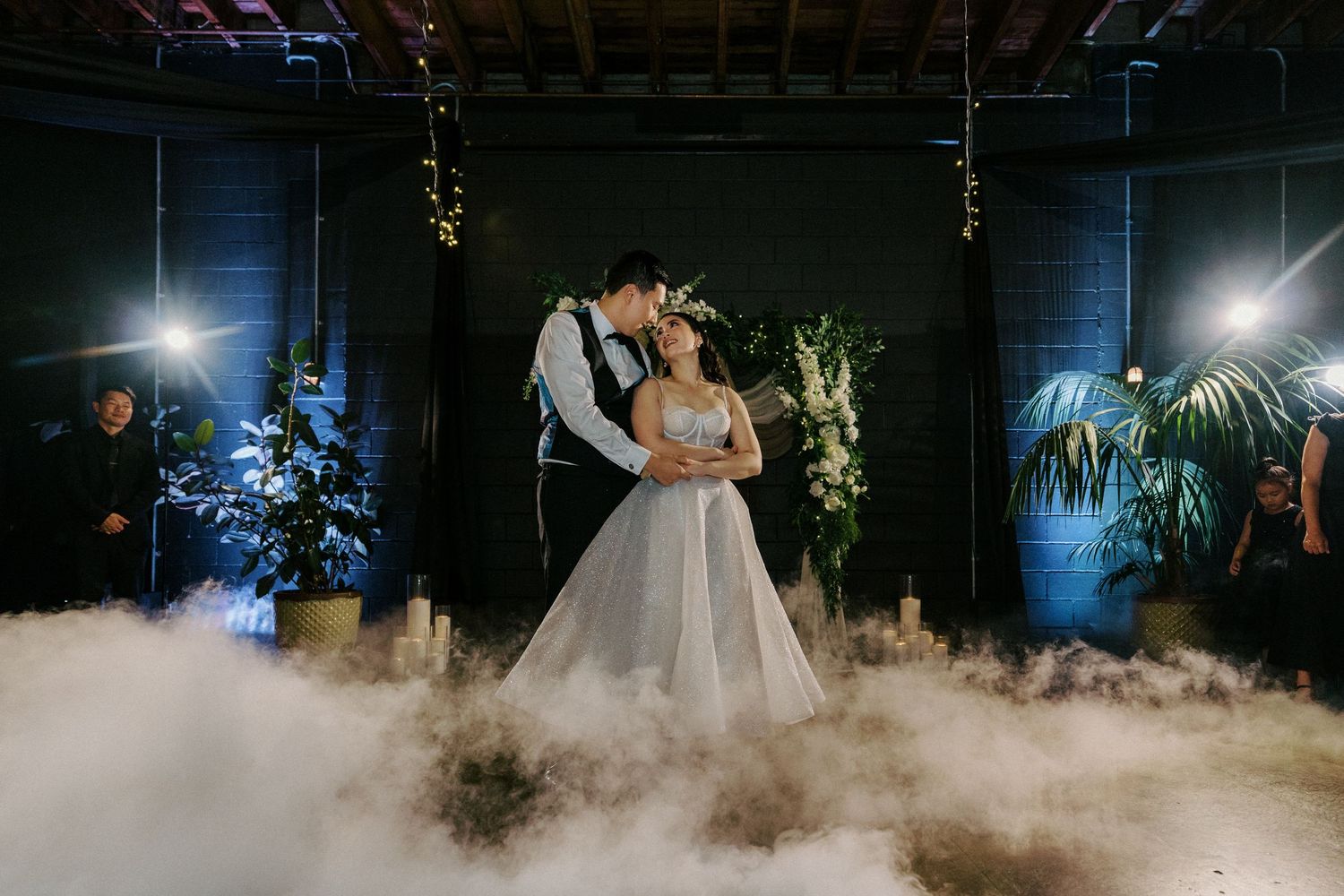 A joyful couple celebrates under a floral arch during their outdoor garden wedding ceremony.