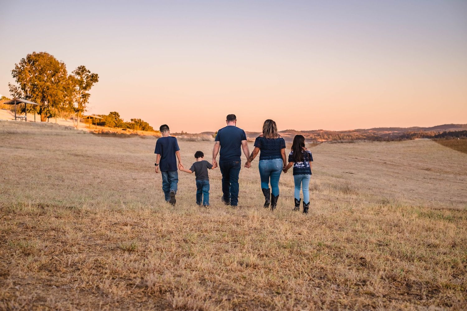 Sue and Carlo walking together with their three children at lake hogan in valley springs california during sunset.
