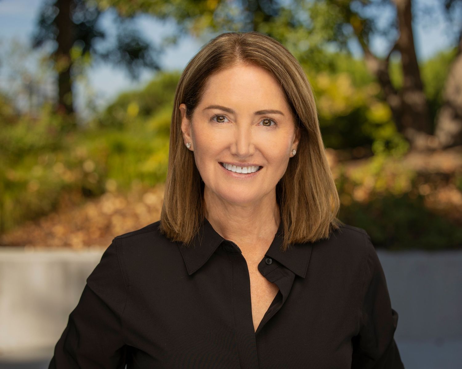 Professional headshot series showing someone in a black blazer against a blurred outdoor background.
