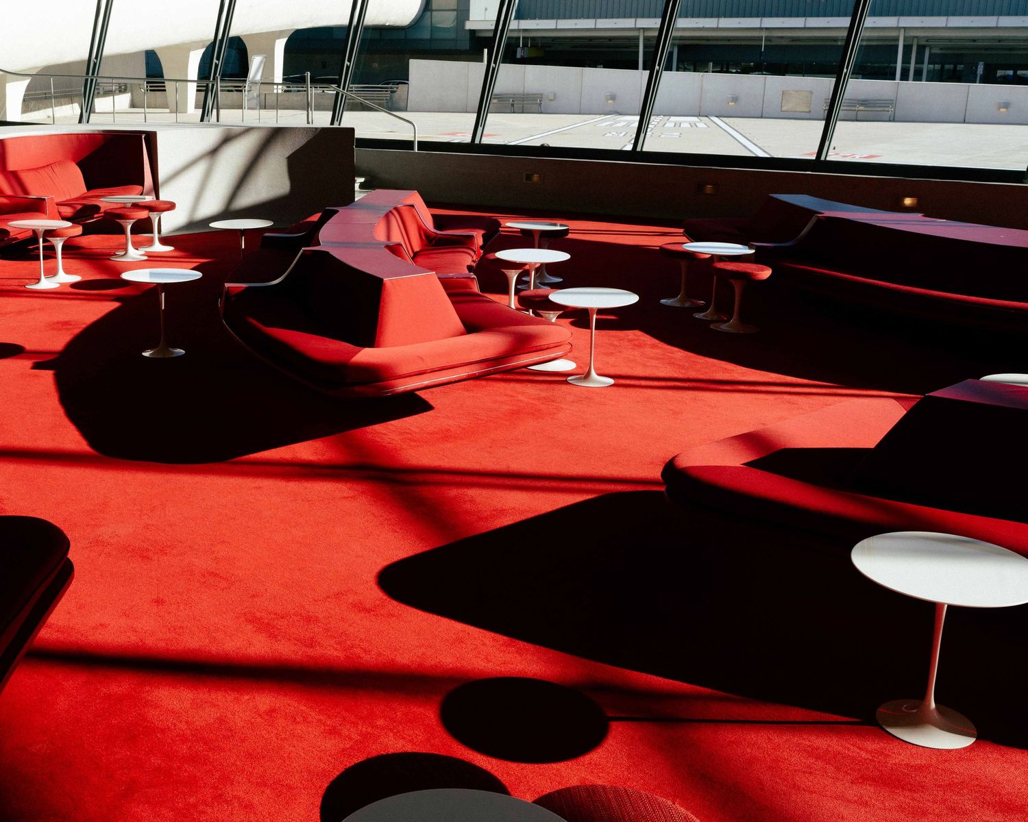 Modern lounge area with bright red carpet and curved seating arrangements.