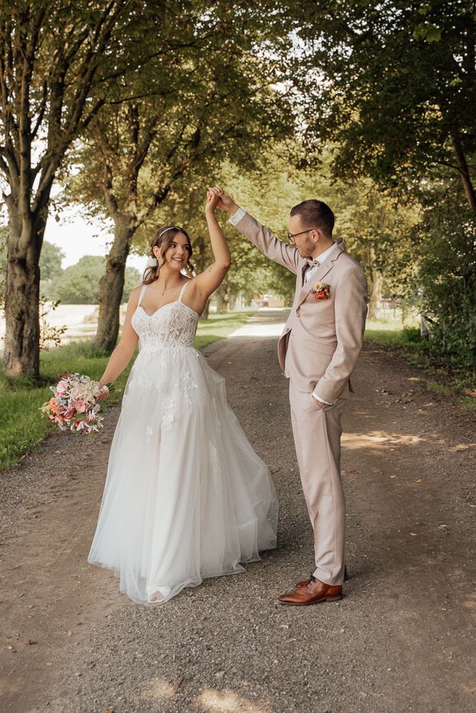 A romantic wedding couple embraces in sunlit garden setting at golden hour.