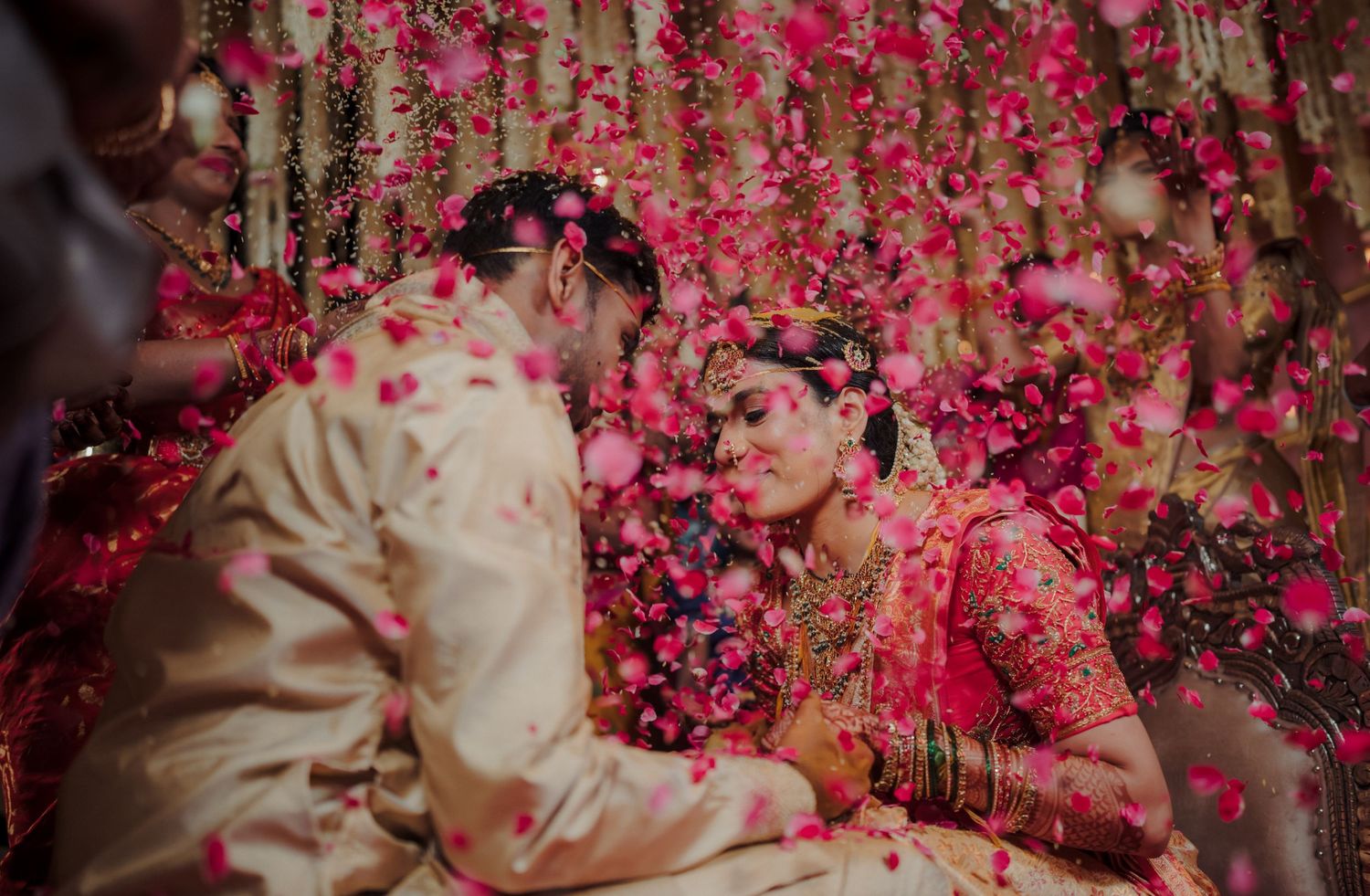 Fluttering pink rose petals shower down on a tender moment during an intimate wedding ceremony.