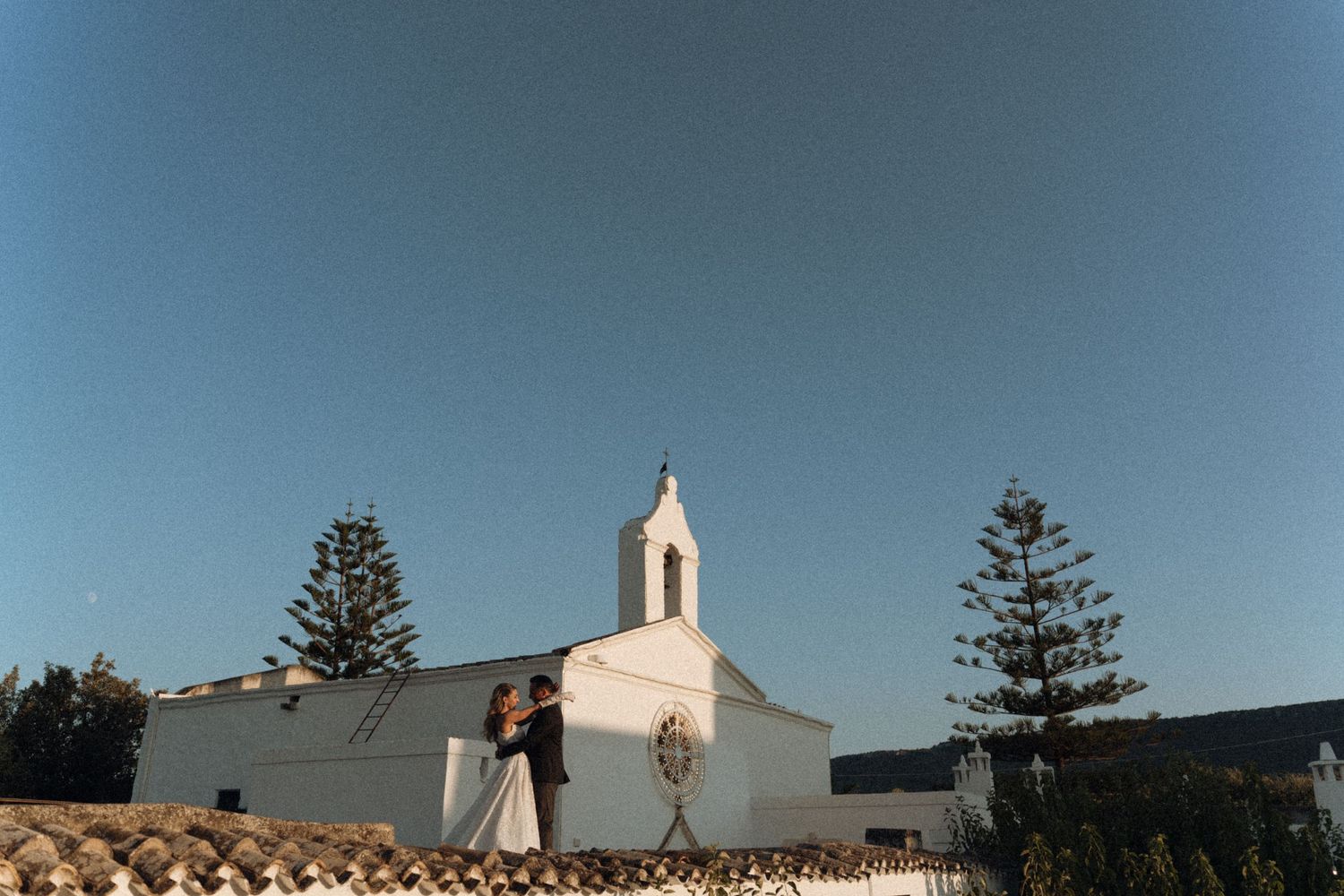 A black and white photo sequence shows silhouettes of figures playfully interacting with a white church steeple against the sky.