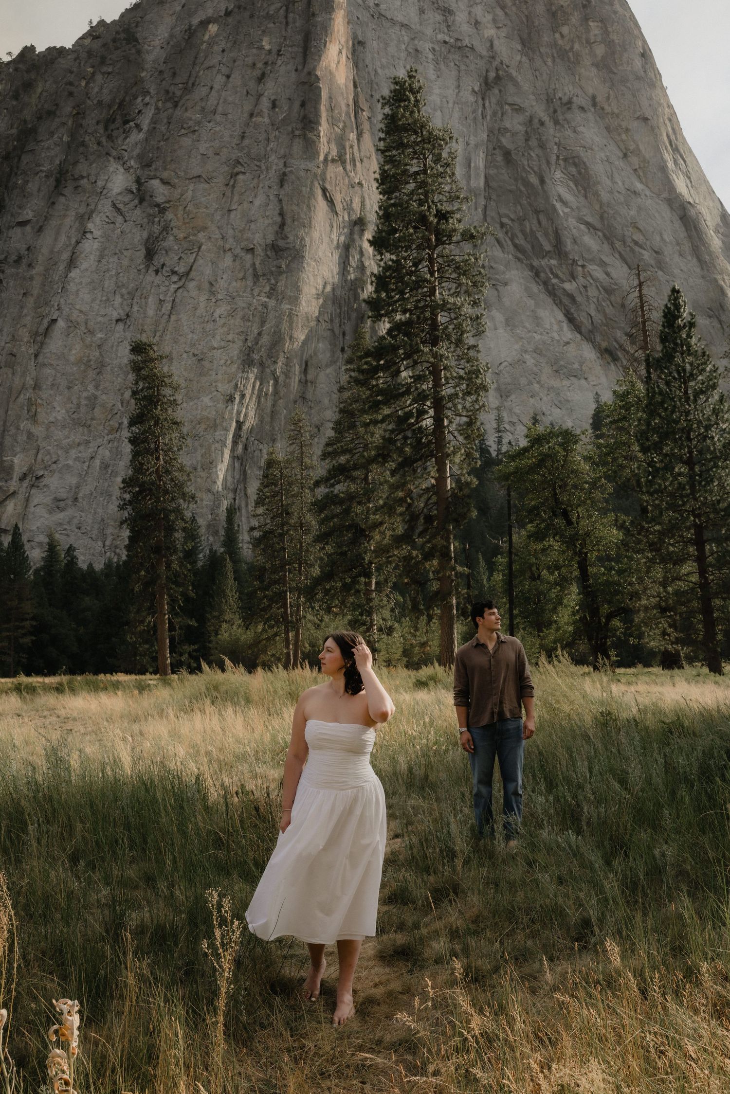 Black and white photo of bride and groom sharing an intimate moment under flowing wedding veil in outdoor field.
