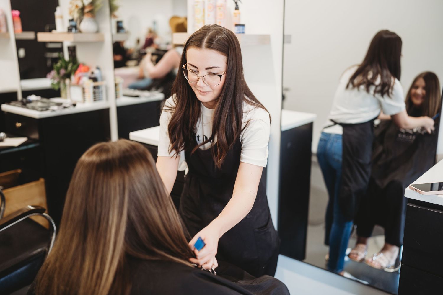 Professional hairstylist working on client's hair in modern salon setting.