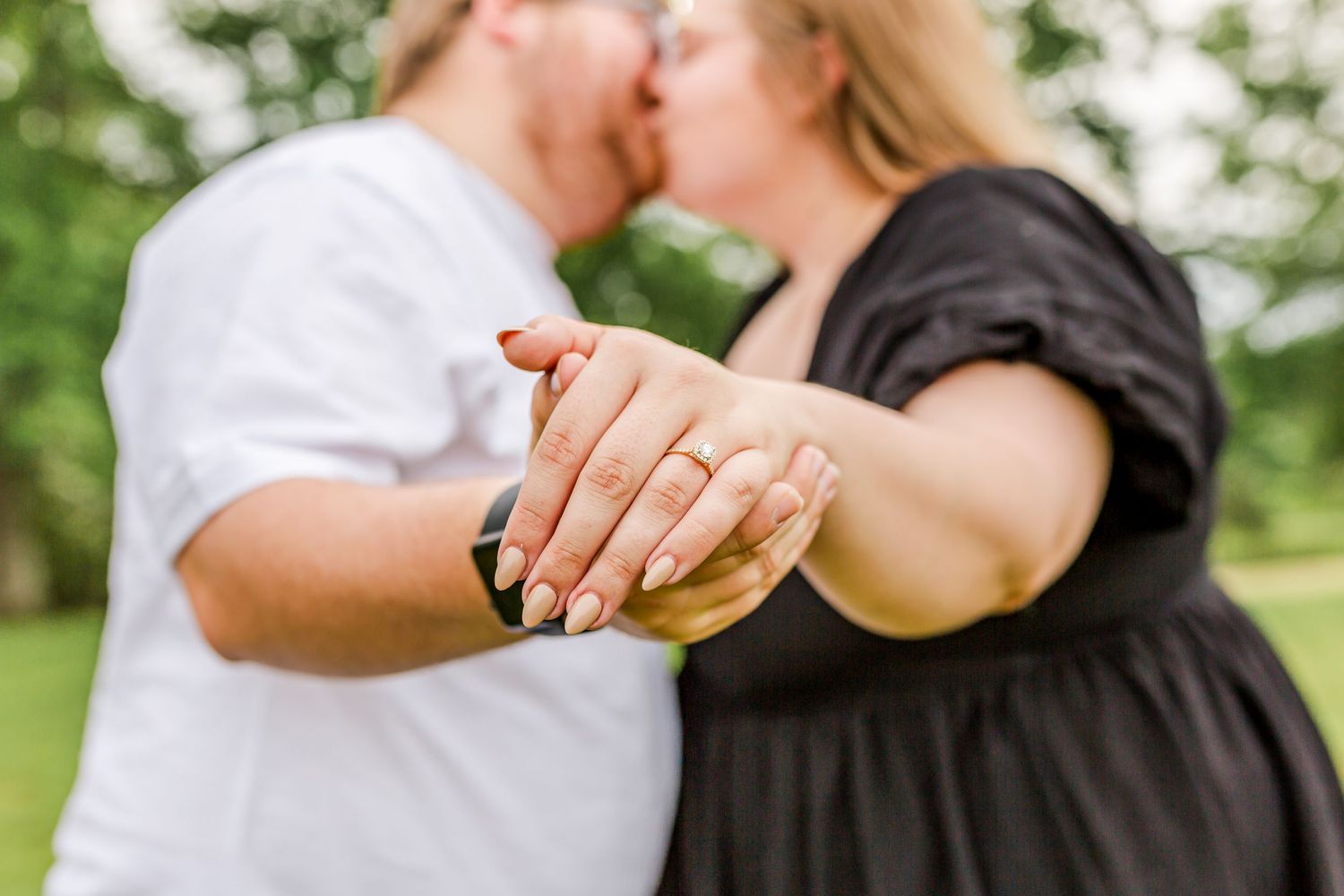 Close-up of hands displaying engagement ring during romantic outdoor moment.