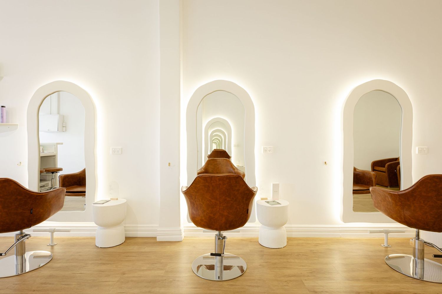 White minimalist interior design with arched doorways and windows creating a bright, modern gallery-like space.