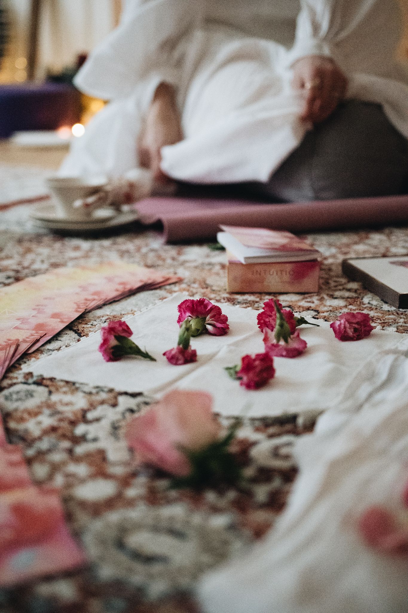 Dried pink rose petals scattered on a vintage patterned tablecloth create a romantic and nostalgic scene.