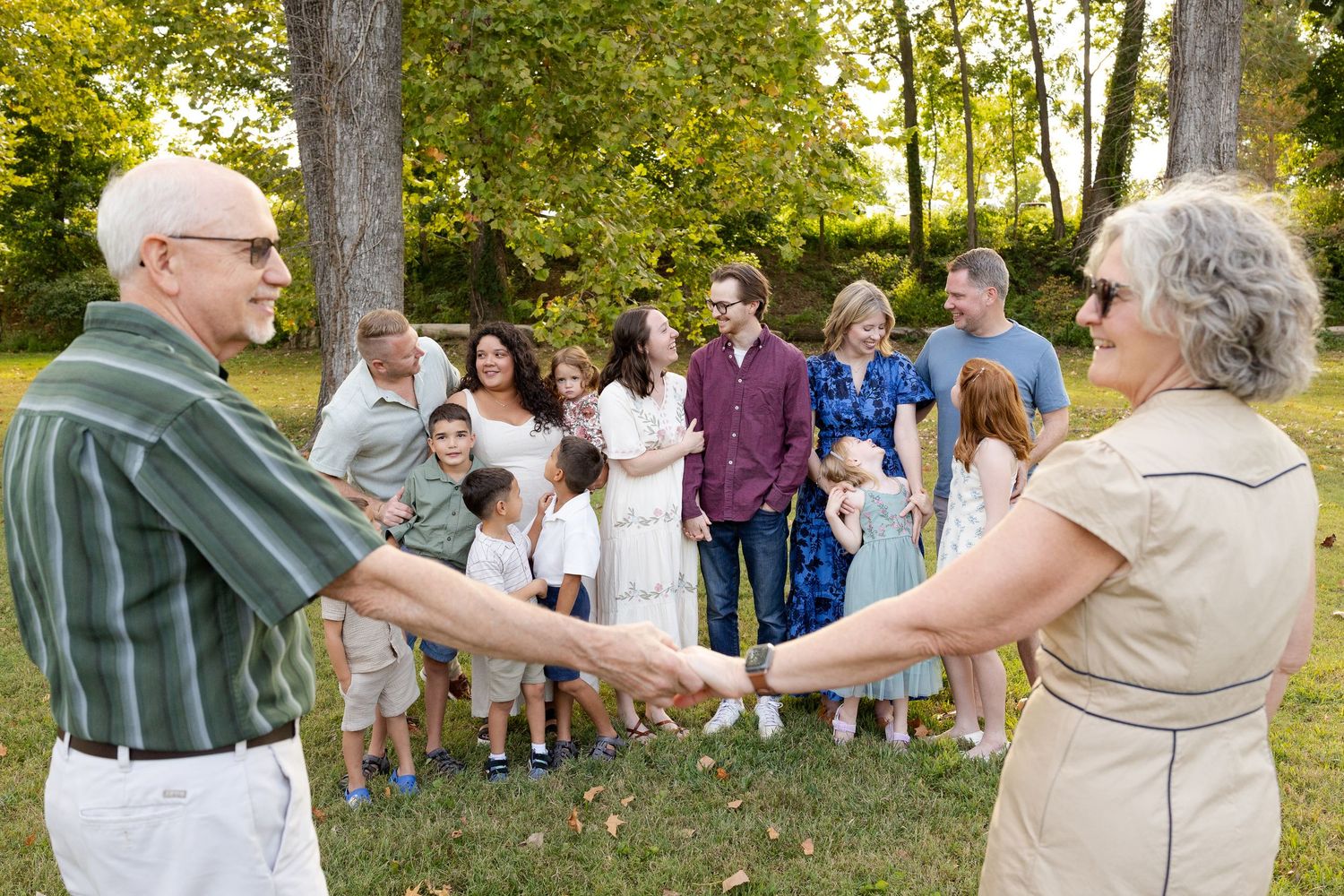 A large extended family wearing coordinated blue and white outfits poses together outdoors for a group portrait.