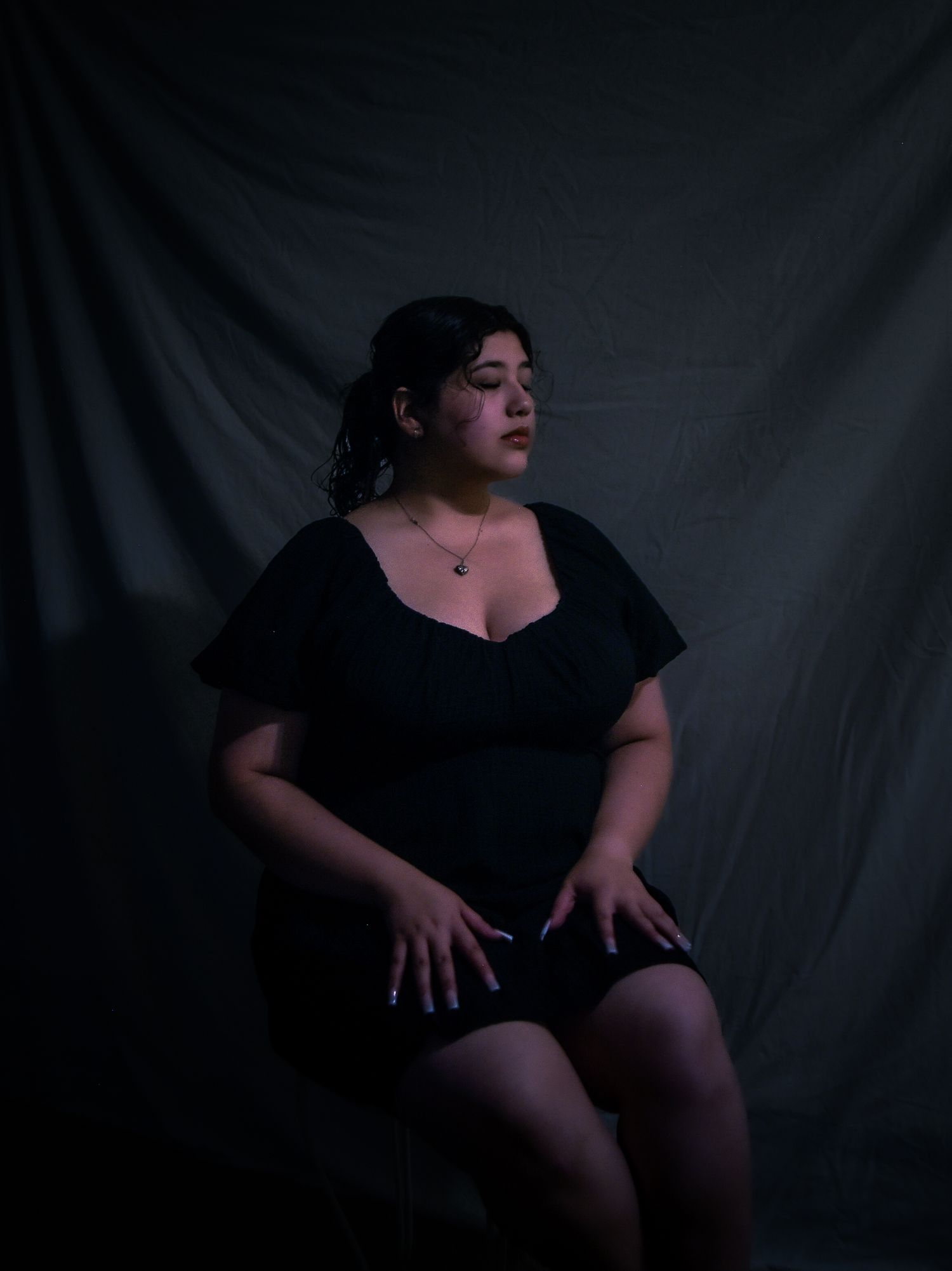 Dramatic black and white portrait series showing figure in dark clothing against shadowy background creating moody atmosphere.