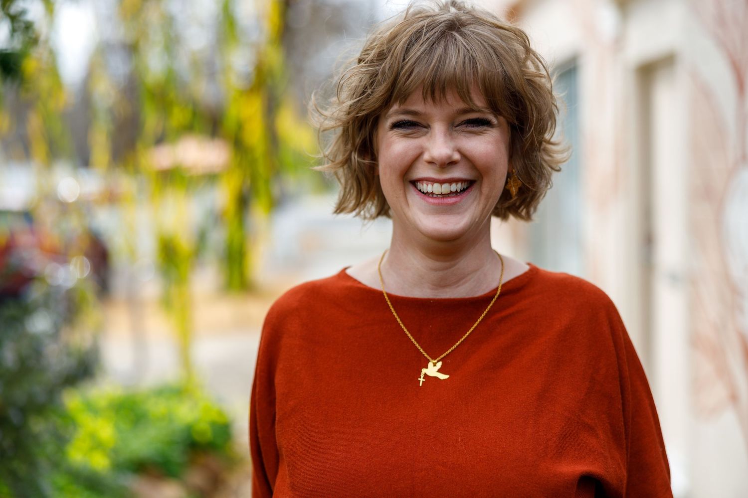 A series of studio portraits featuring someone wearing a vibrant orange sweater in an outdoor garden setting.