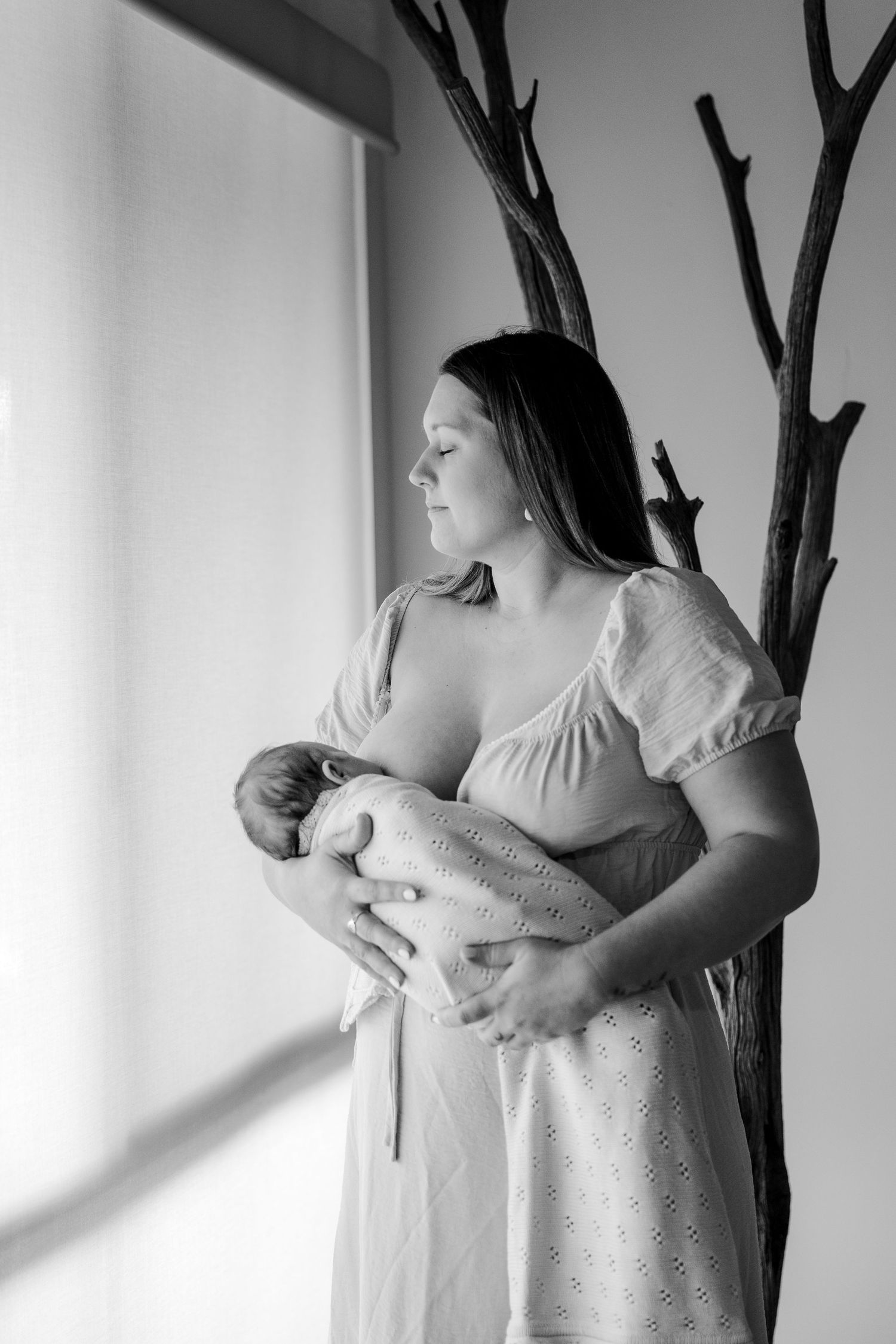 A tender moment of a newborn baby breastfeeding, shown in an intimate close-up photograph.