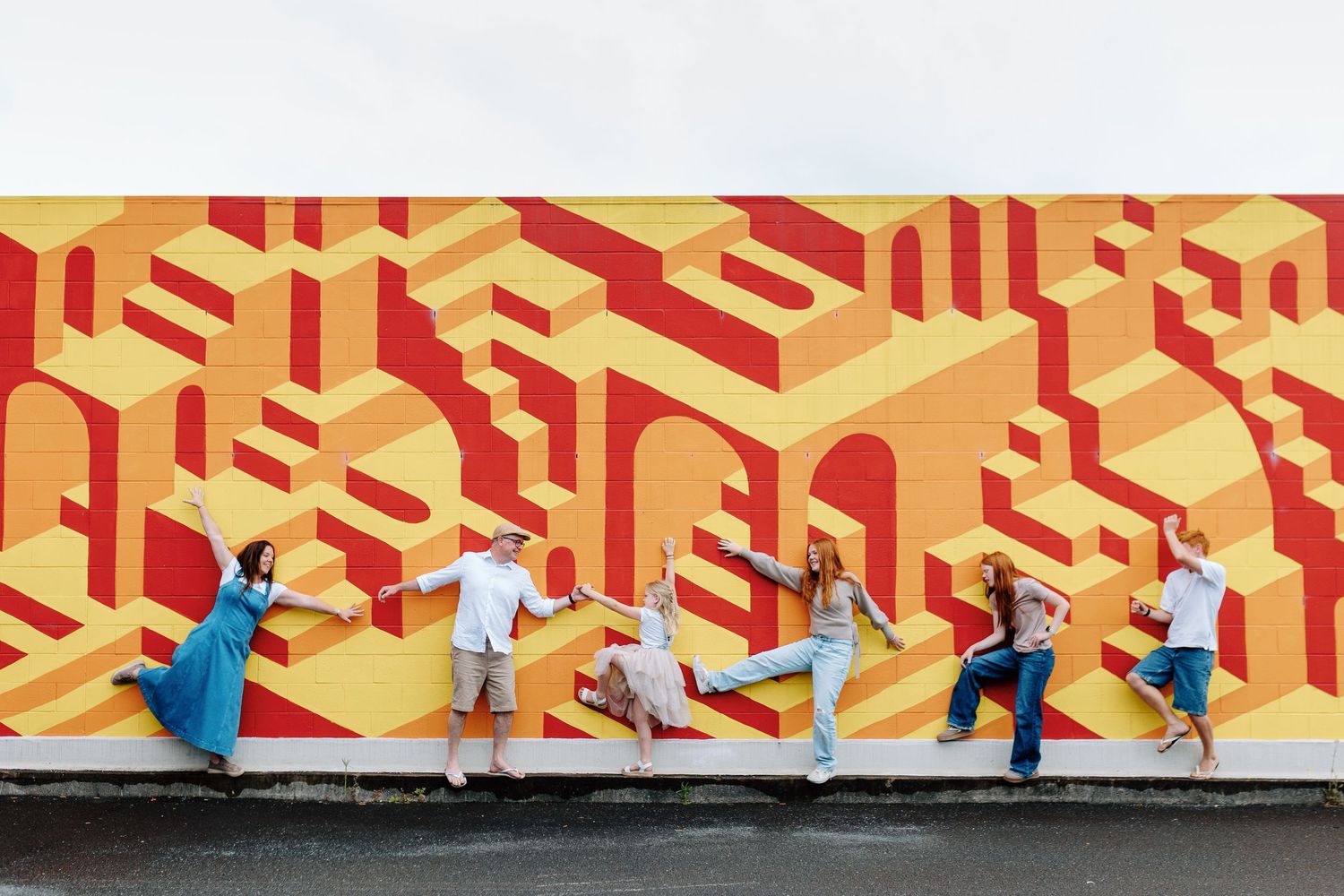 Colorful geometric isometric artwork installation featuring yellow and red patterns with small figures walking through.