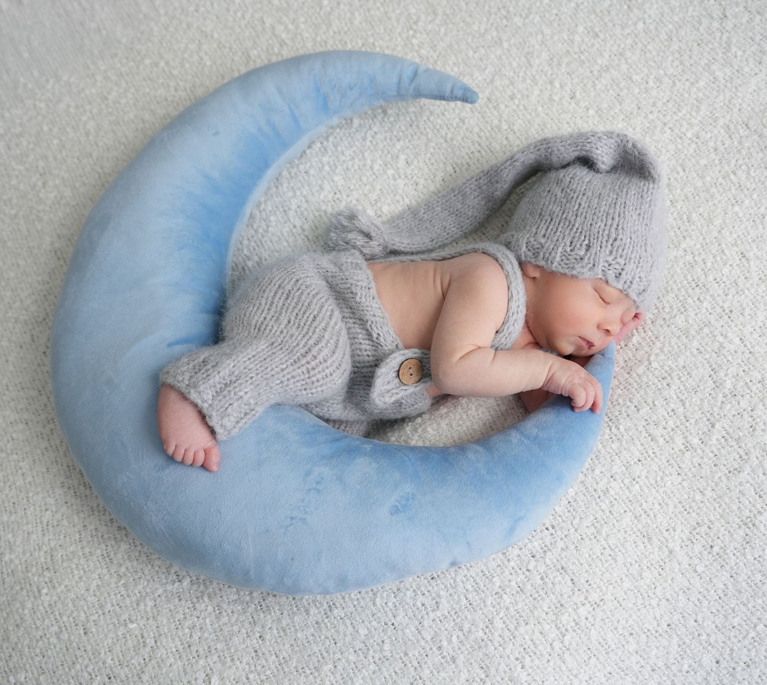 A sleeping baby nestled in a curved blue nursing pillow shown in progressive positions from left to right.
