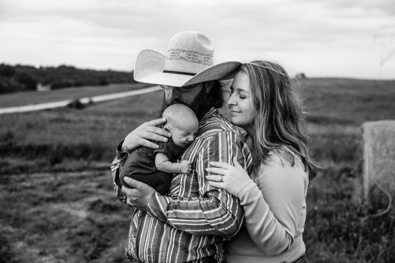 A black and white photo montage showing a romantic couple embracing in a rustic field wearing cowboy hats.