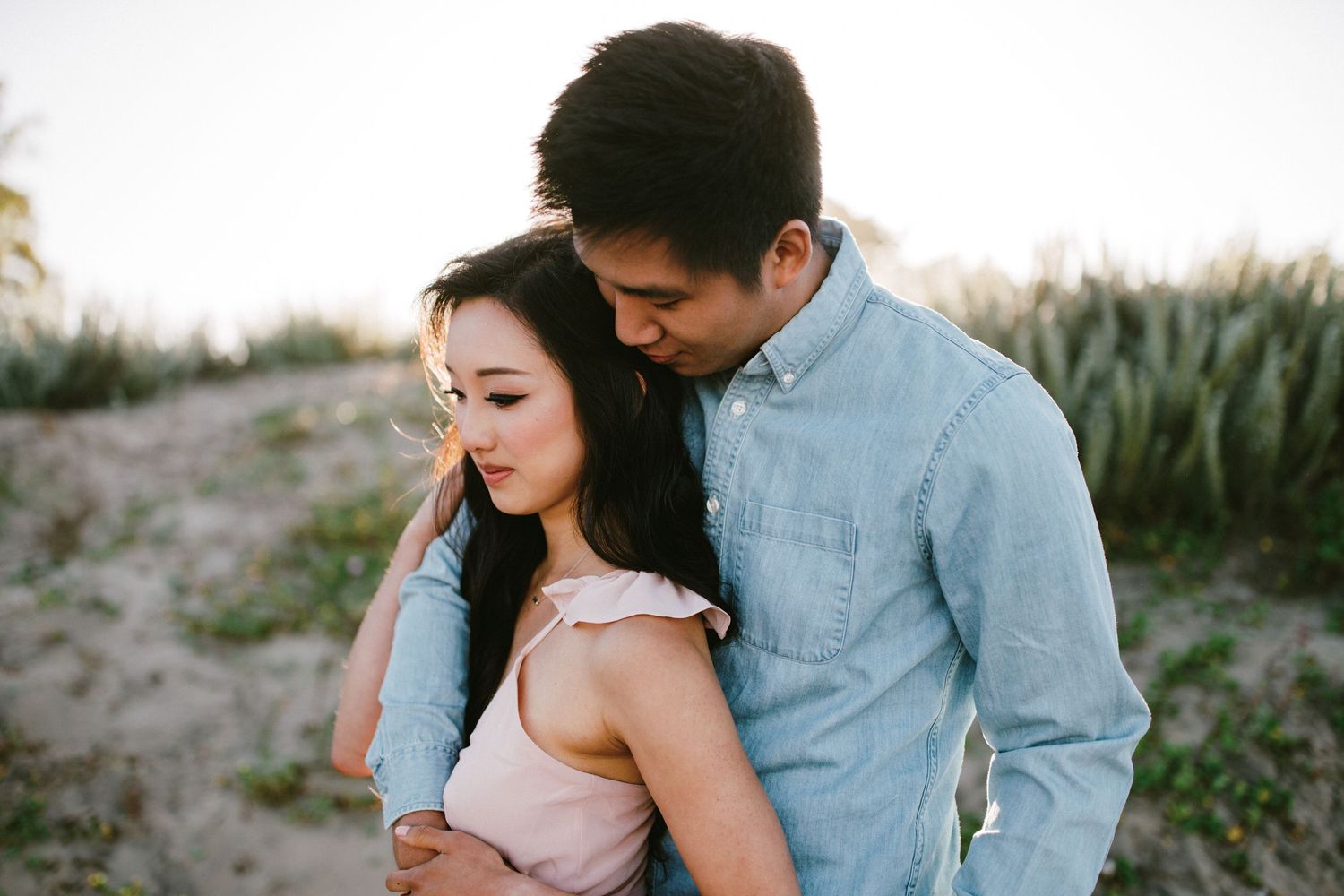 An intimate portrait of a couple embracing outdoors during golden hour.