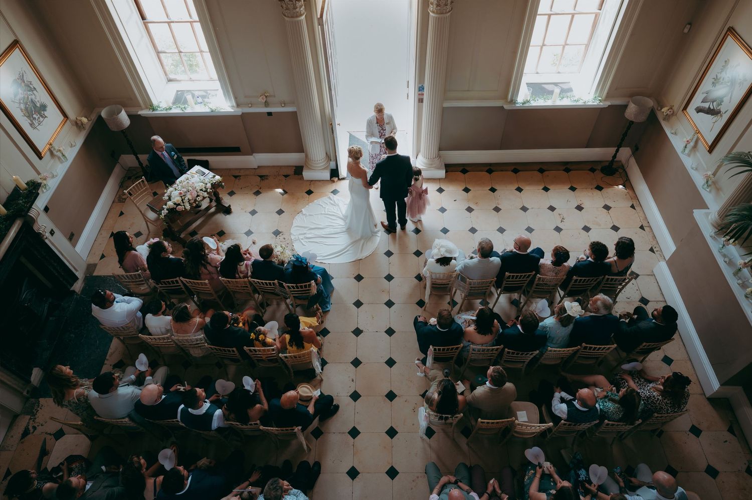 Bride and groom celebrate at rustic barn wedding ceremony, raising hands joyfully with guests seated nearby.