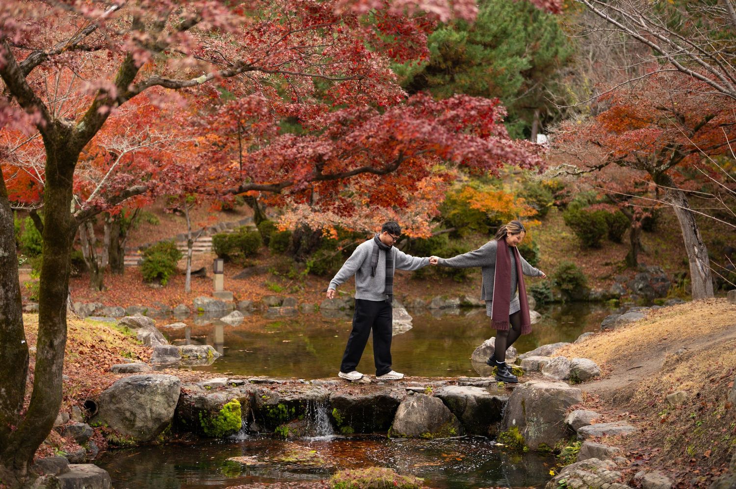 Couple standing together in a traditional Japanese garden with a historic pagoda-style building in the background.