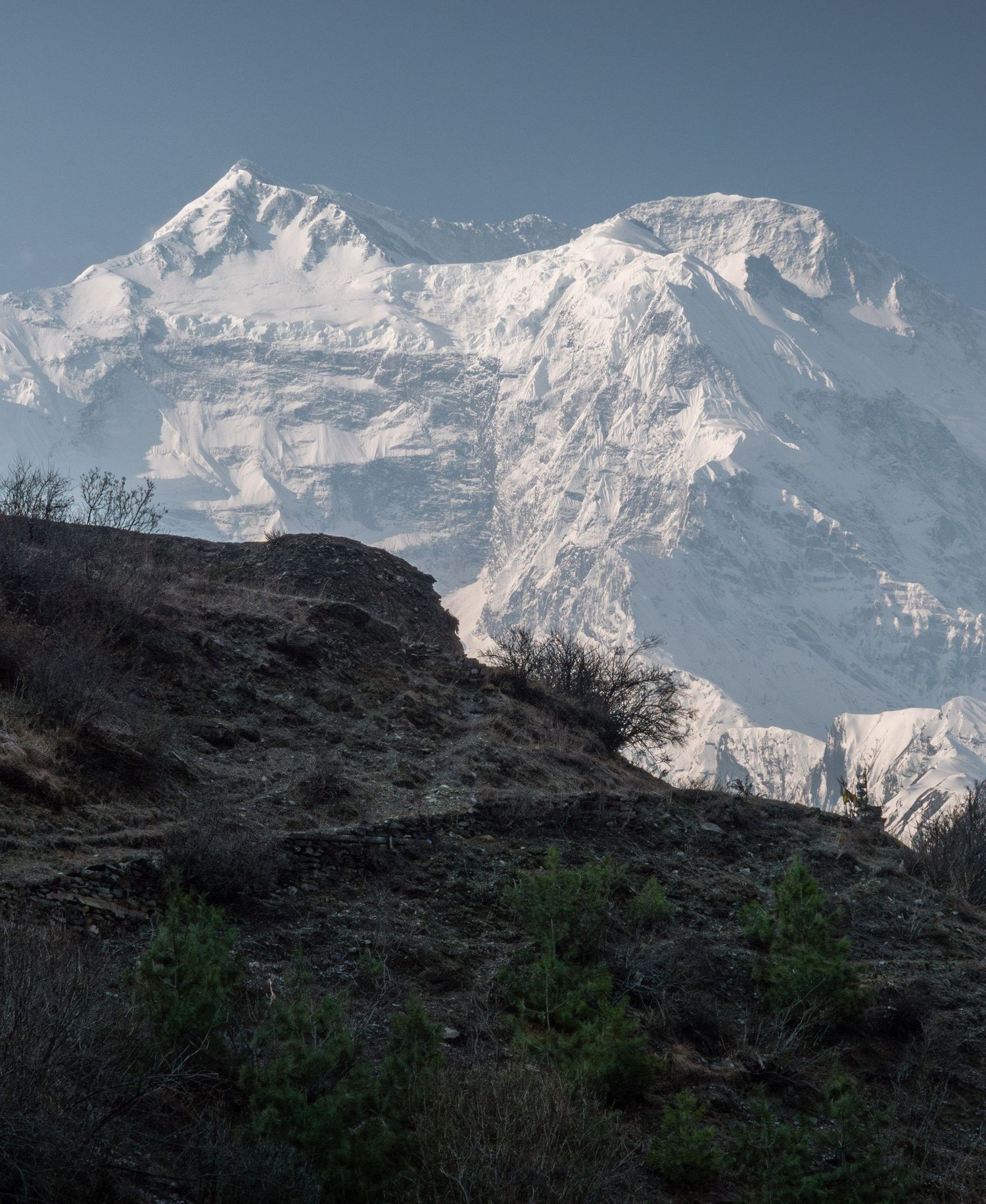 Snow-covered Himalayan peak rises majestically against a clear blue sky.