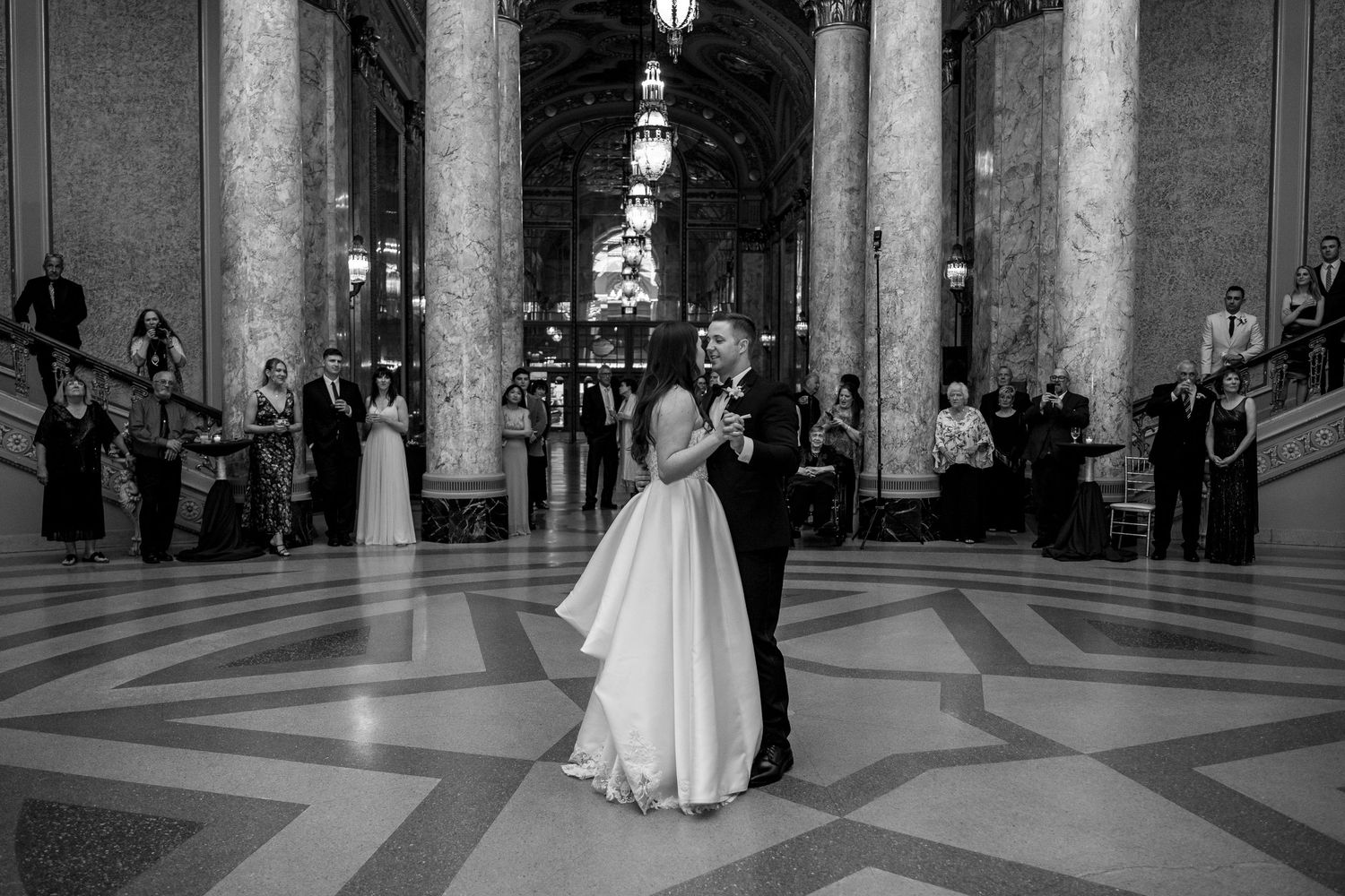 Wedding celebration outside a brick building with guests throwing confetti.