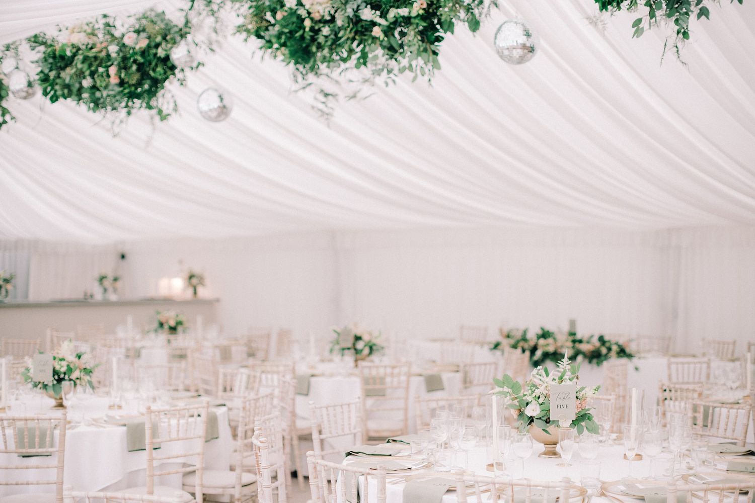 Elegant white wedding reception tent Fox Harb'r Resort wedding draped fabric ceiling, hanging greenery and white floral arrangements.
