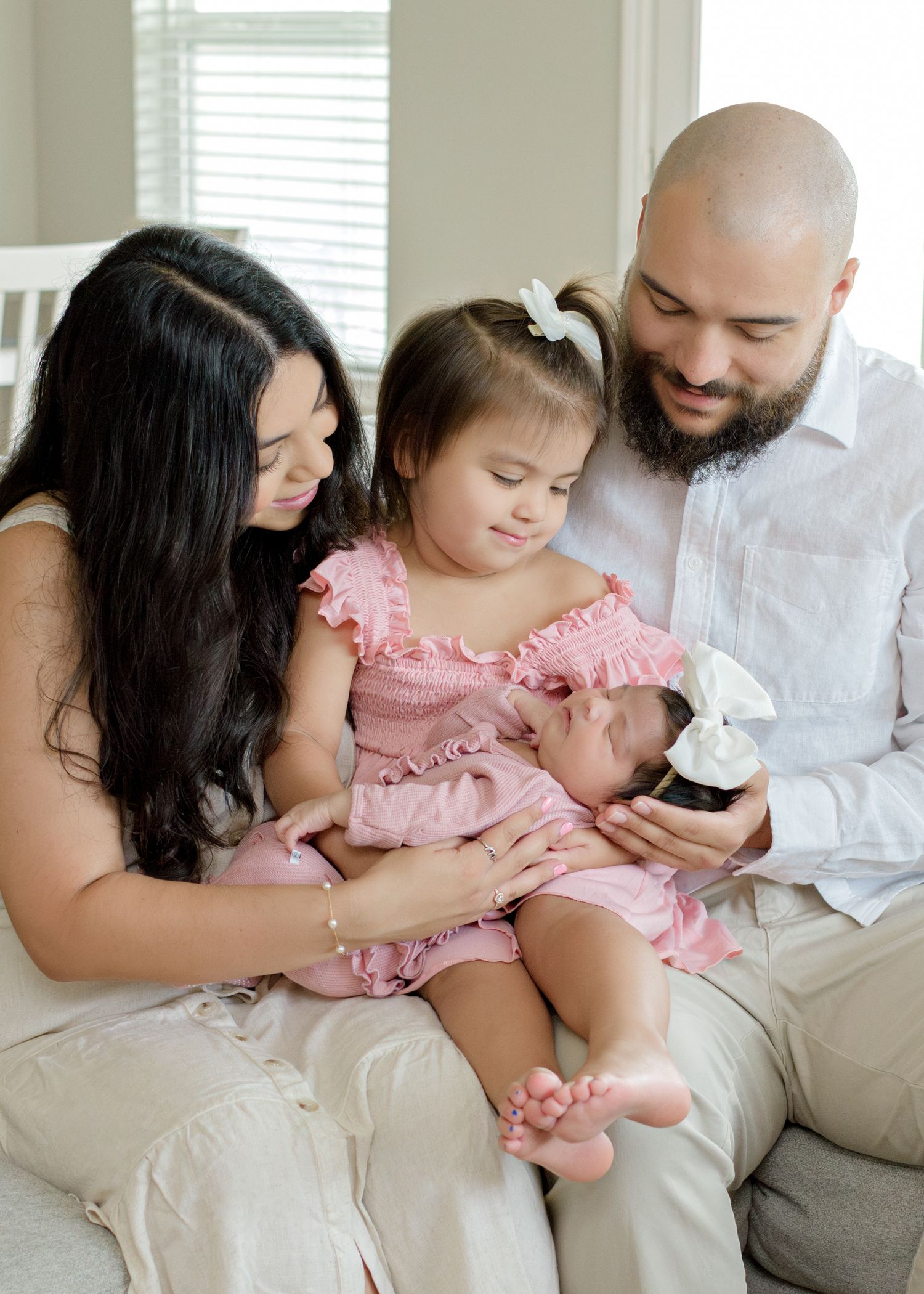 A family bonding moment on the couch while looking at their newborn baby.