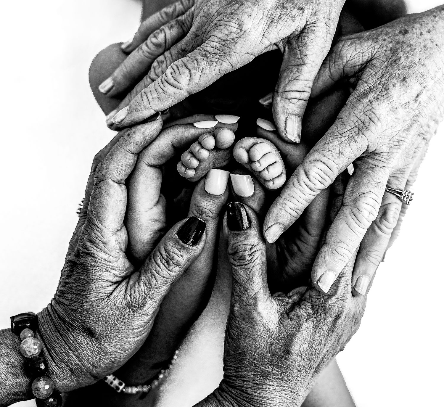 Black and white image of multiple generations' hands joining together in unity.