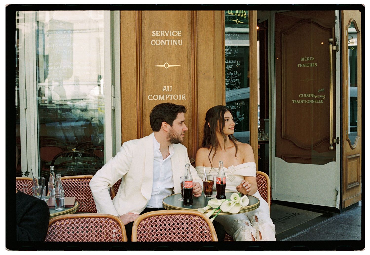 Couple sitting at a Parisian café terrace, enjoying drinks together in an elegant outdoor setting.
