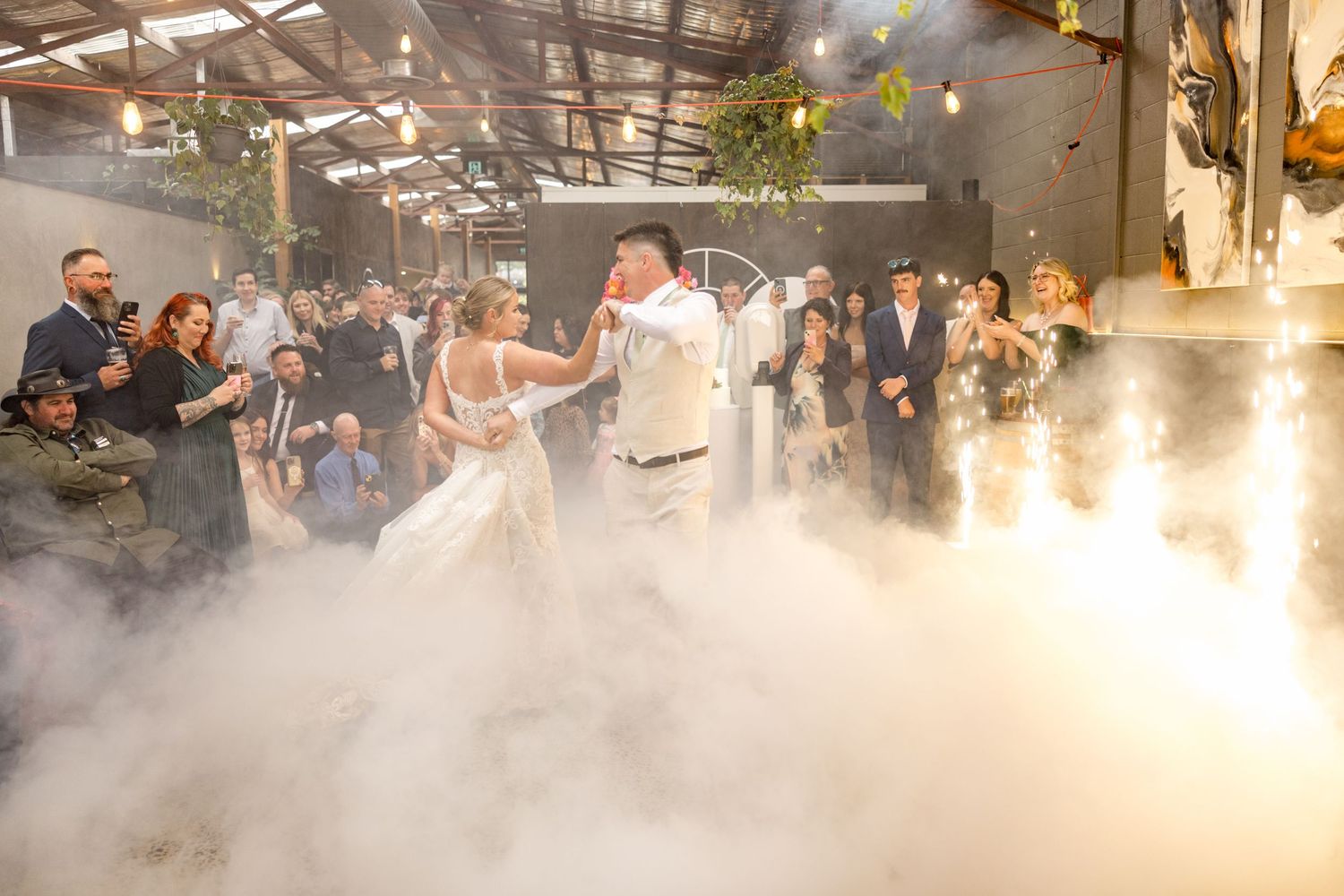 A group of people dance and celebrate in a misty outdoor setting with atmospheric lighting and fog effects.