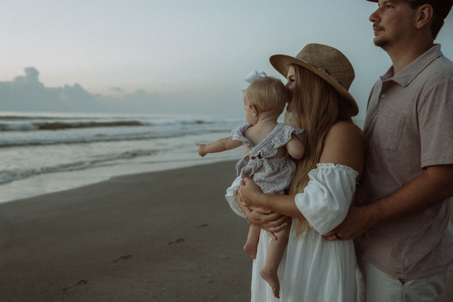Family enjoying a sunset beach session with waves rolling in on the shore. Watching the sunrise as their firstborn turns one in Florida
