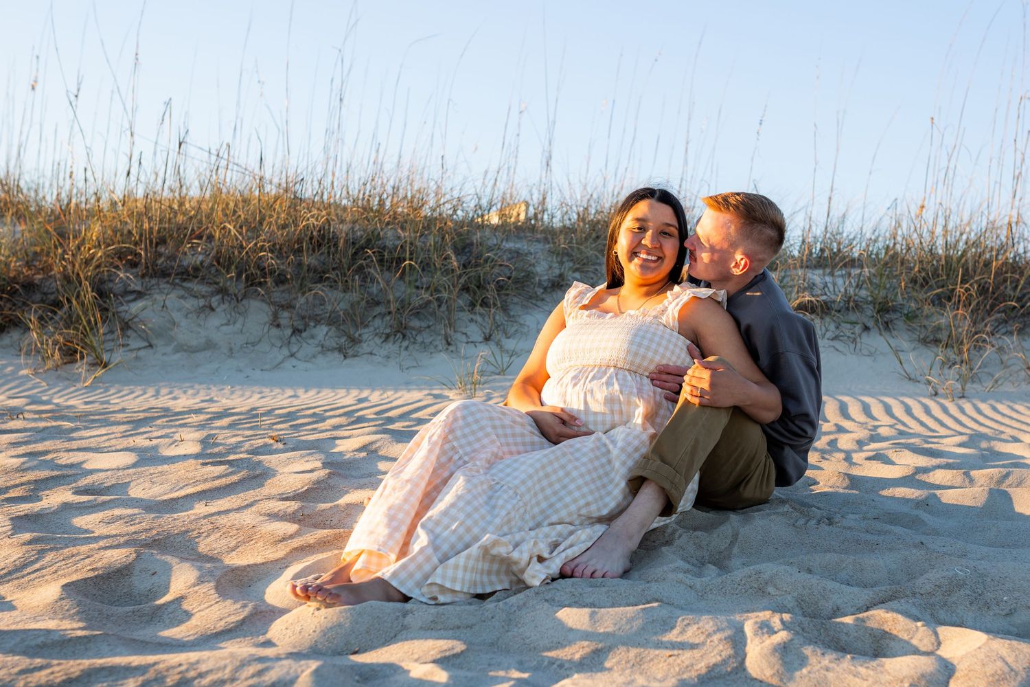 Pregnant mother walking along the shoreline during a sunset beach maternity session in Emerald Isle, North Carolina with soft natural light