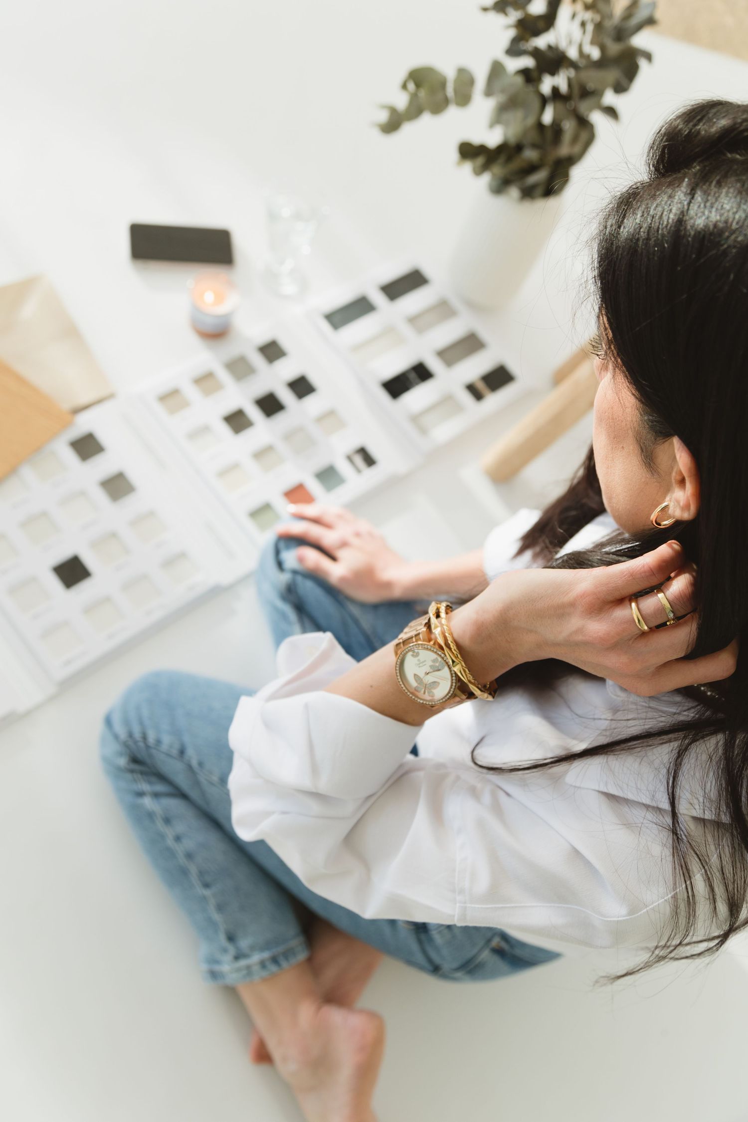 Person wearing white shirt and jeans relaxes while looking at photo prints laid out on white surface.