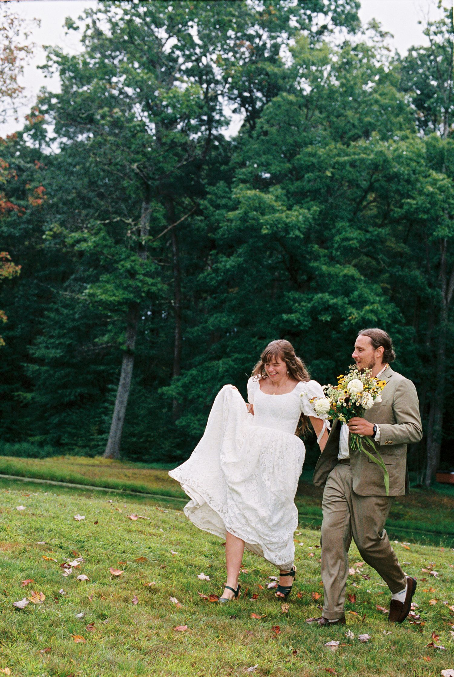 A wedding ceremony in a wooded setting with white draped fabric decor and a Persian rug aisle runner.