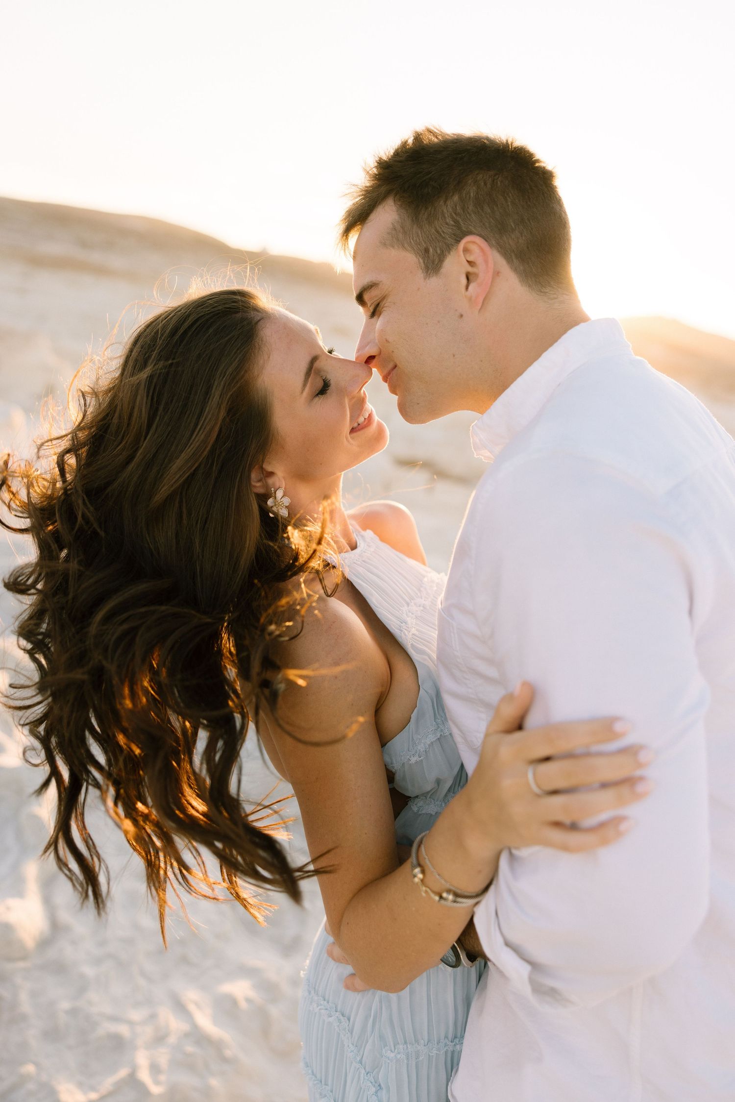 Wedding couple stands under floral arch with baby's breath against wooden doors.