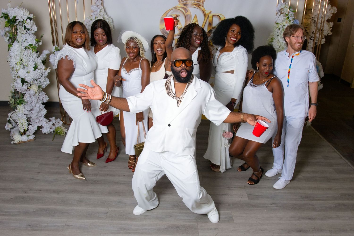 People dancing at an all-white party, with a woman in white romper enjoying the celebration under blue lights.